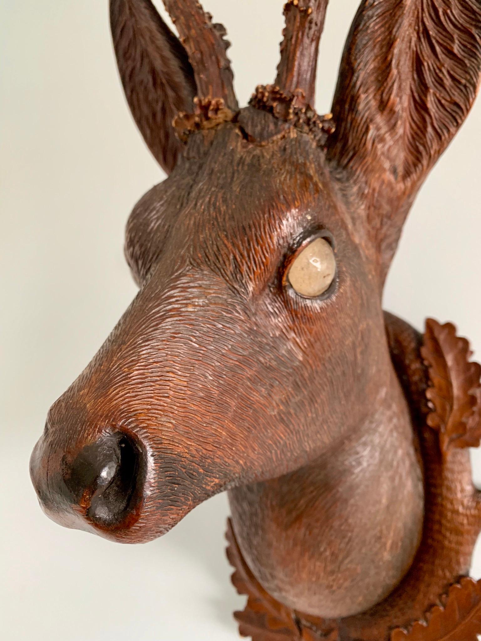 Hand carved Bavarian wood Deer head with real antlers on plaque. The execution is excellent with fur tinted to imitate natural coloring. The eyes are glass. The plaque is carved with oak leaves.