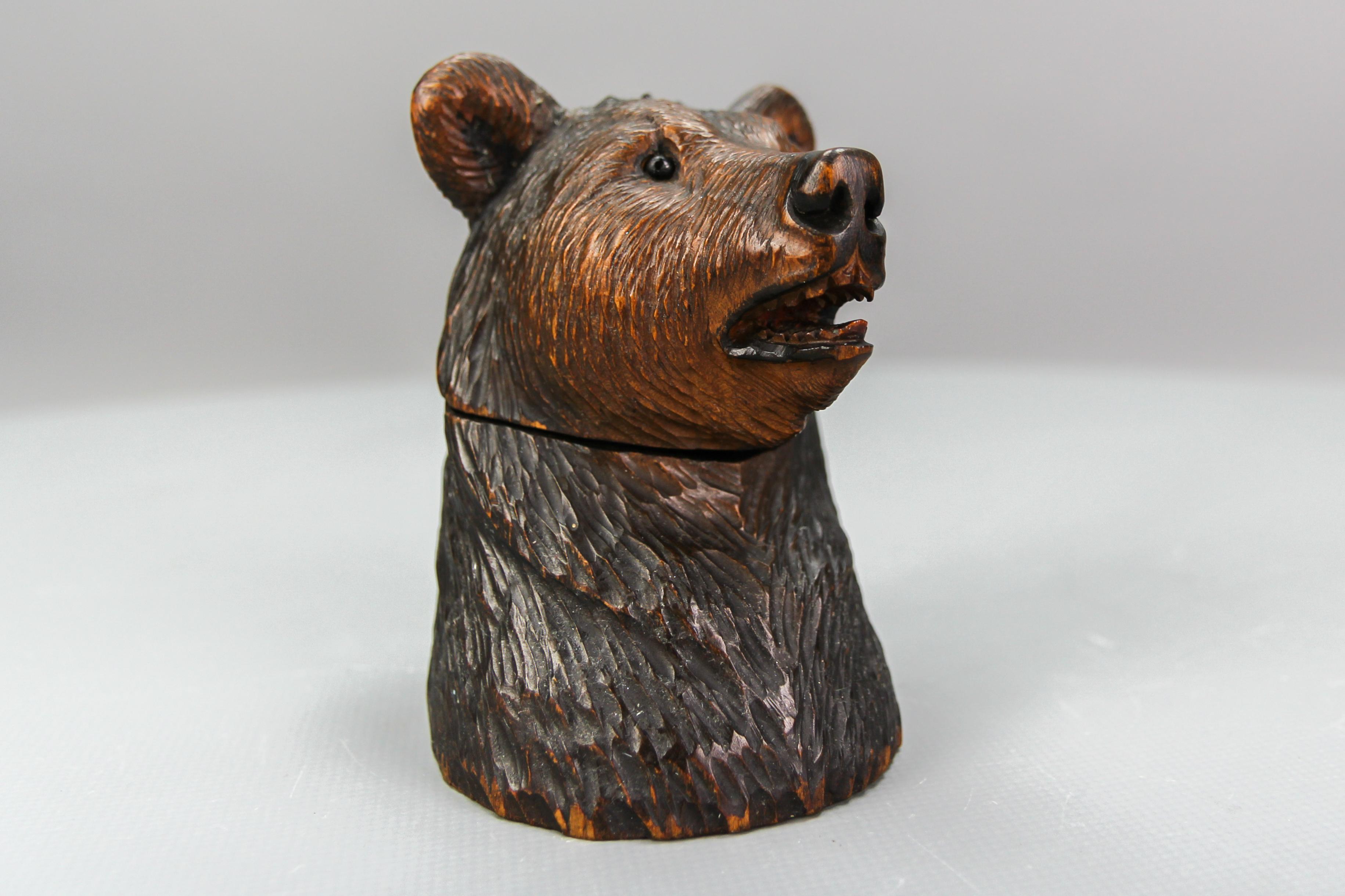 The Black Forest carved wood figural humidor in the shape of a bear head with glass eyes, circa 1920.
This antique, dark brown, linden wood humidor is masterfully carved and features a detailed head of a bear with glass eyes. The bear's head can be