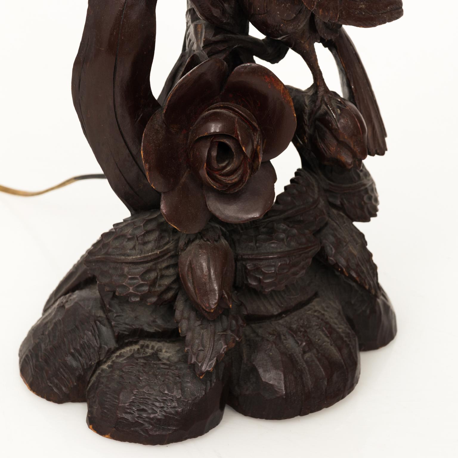 German Black Forrest carved hardwood lamp with birds perched in a floral setting, circa 1880-1890. Matching shade is included.
 