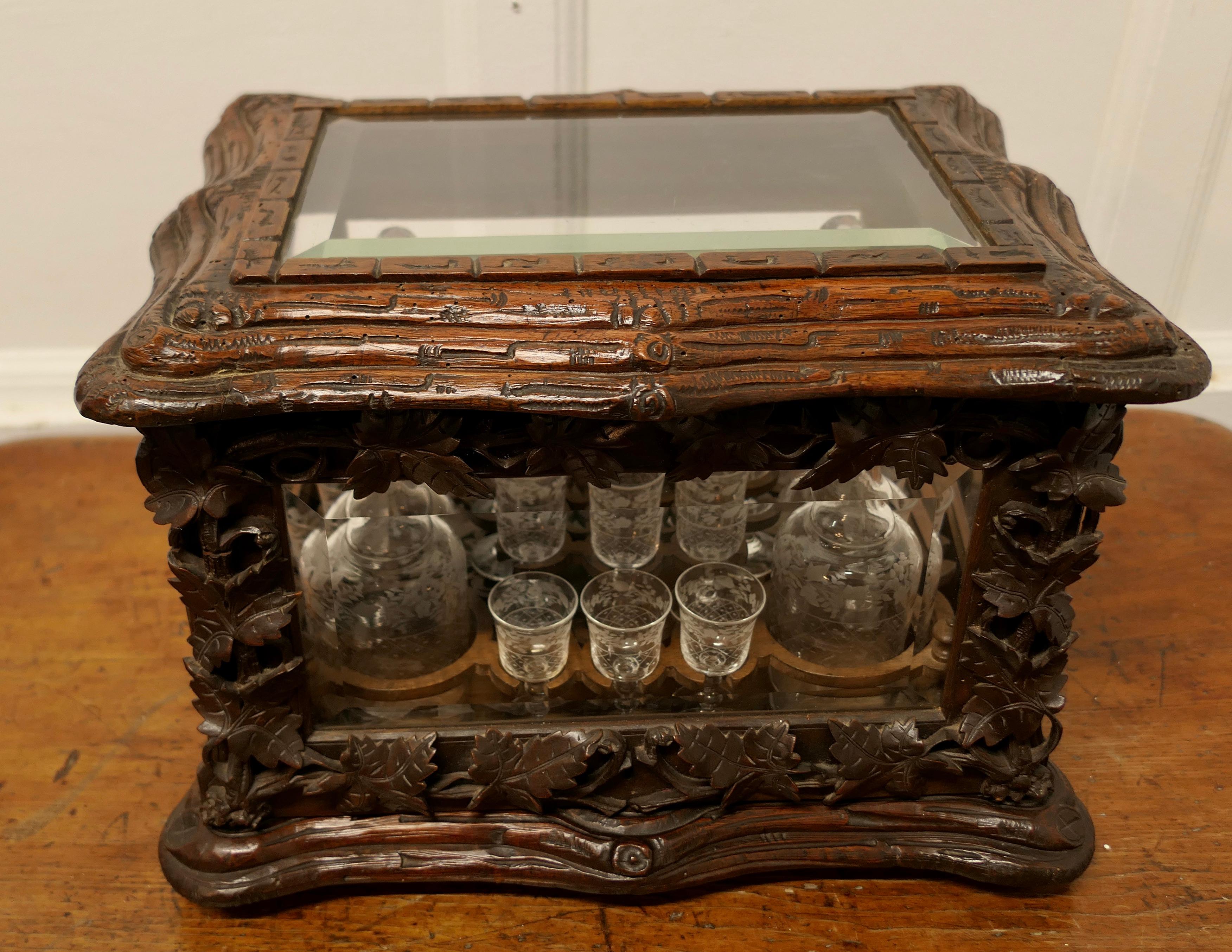 Black Forest “Cave de Liqueur” 

This is a wonderful piece of Craftsmanship it is a Carved Tantalus or Cave de Liqueur with 4 Decanters and 16 Shot Glasses

The cabinet has bevelled Glass panels to the front back and sides with charming Carved