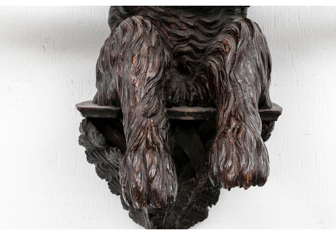 A remarkable Black Forest coat rack with fine and powerful all-over carving. A carved Scotty type dog is seated on a carved bracket and sits up with a twig in its mouth. Its front paws are hanging over a horizontal branch with four hooks. There are