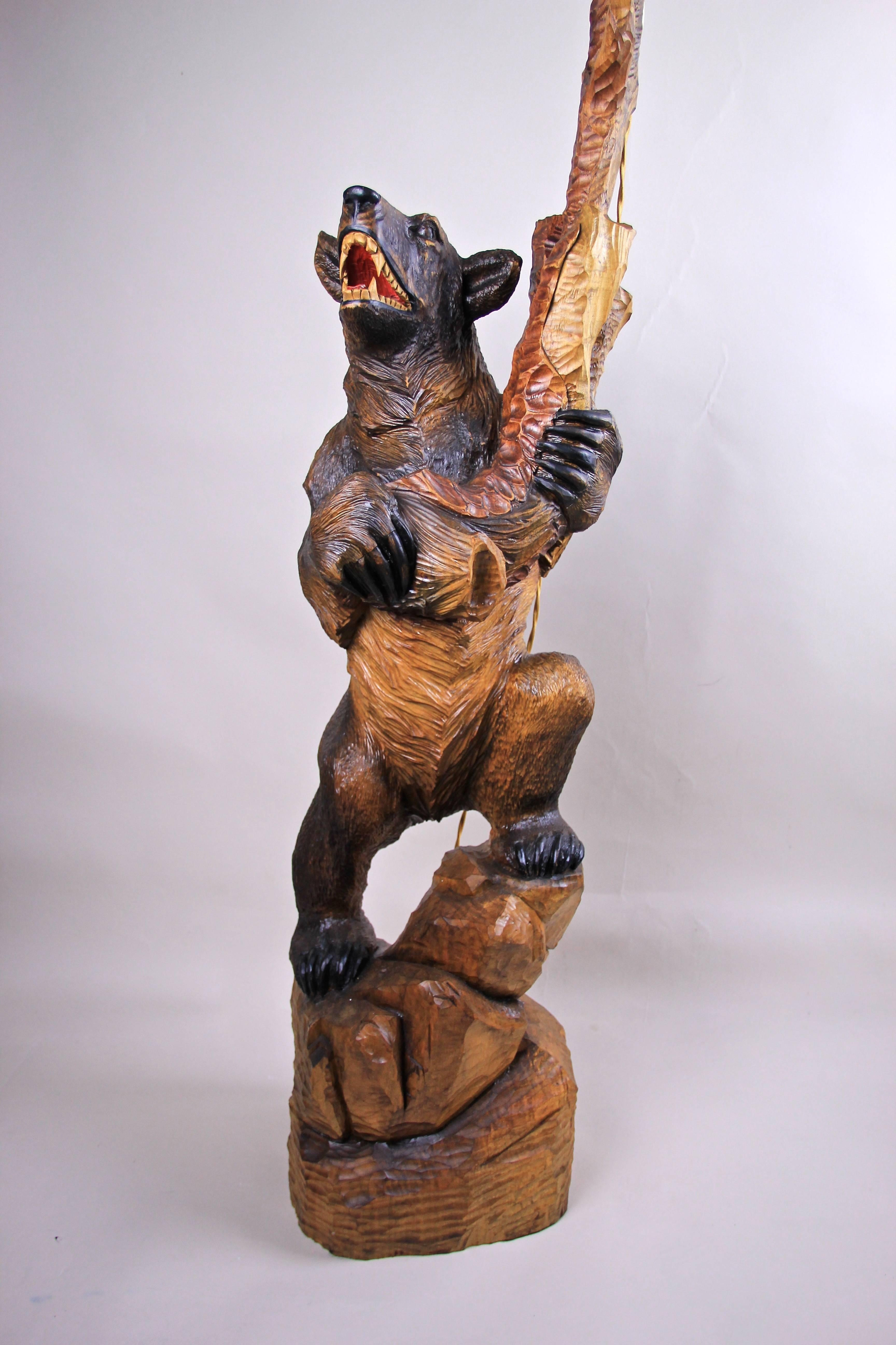 Exceptional Black Forest floor lamp from Bavaria/ Germany, circa 1940. This large hand-carved lamp is definitely an unusual piece shaped out of one big piece of wood. A bear stands on a stump holding a big tree limb which holds the renewed