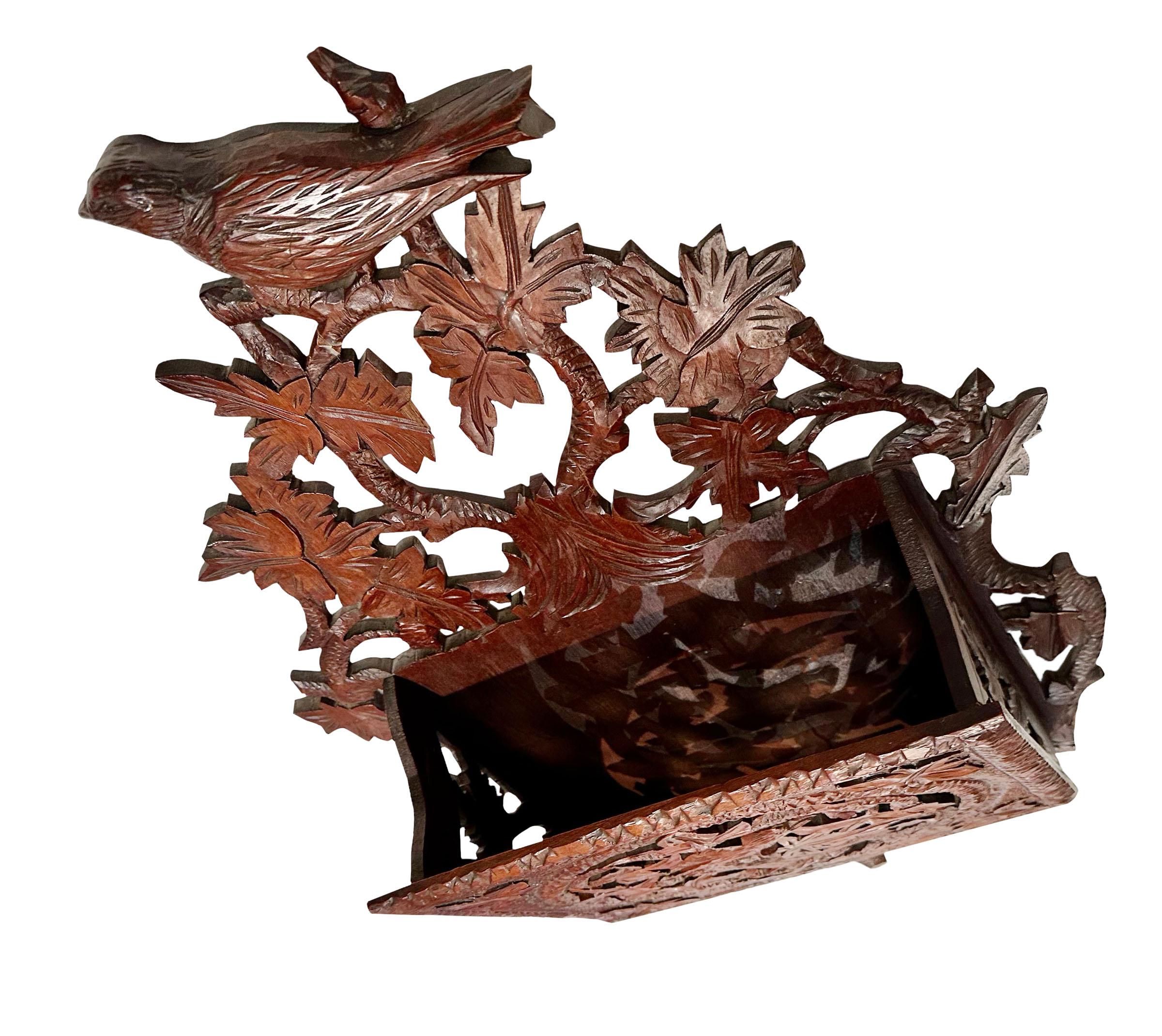 An 1890s German, Black Forest carved wooden newspaper and magazine rack with intricate carvings and a birds, vines and leaves.