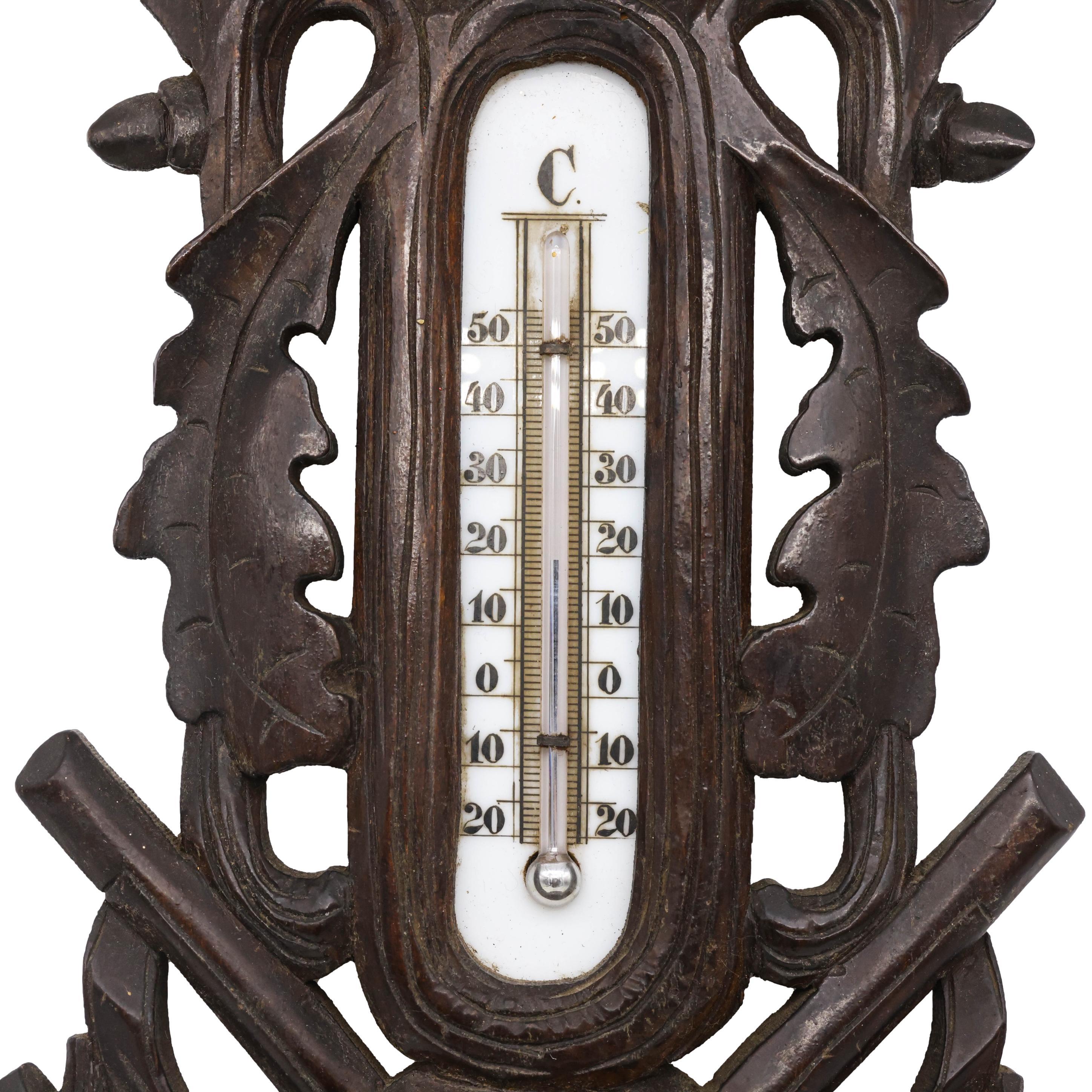 Black Forest Hand-Carved Barometer and Thermometer, the case with crossed shotguns and a hunting game bag, with carved oak leaves, surmounted by a stag's head; the barometer by G. Keller, Paris, with 1.63-in silvered and die-struck dial annotated in