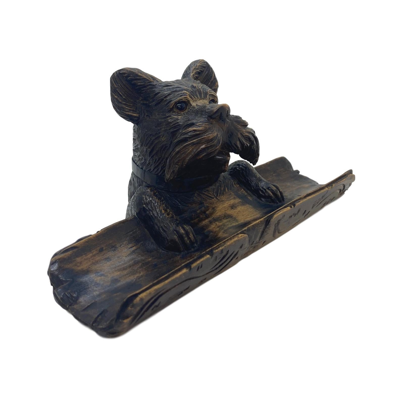 Black Forest hand carved terrier inkwell stand with glass eyes, Swiss, circa 1880. This highly sought-after piece features an adorable and detailed, crisply carved dog with a stylized mustache and beautiful glass eyes, the hinged top opens to reveal