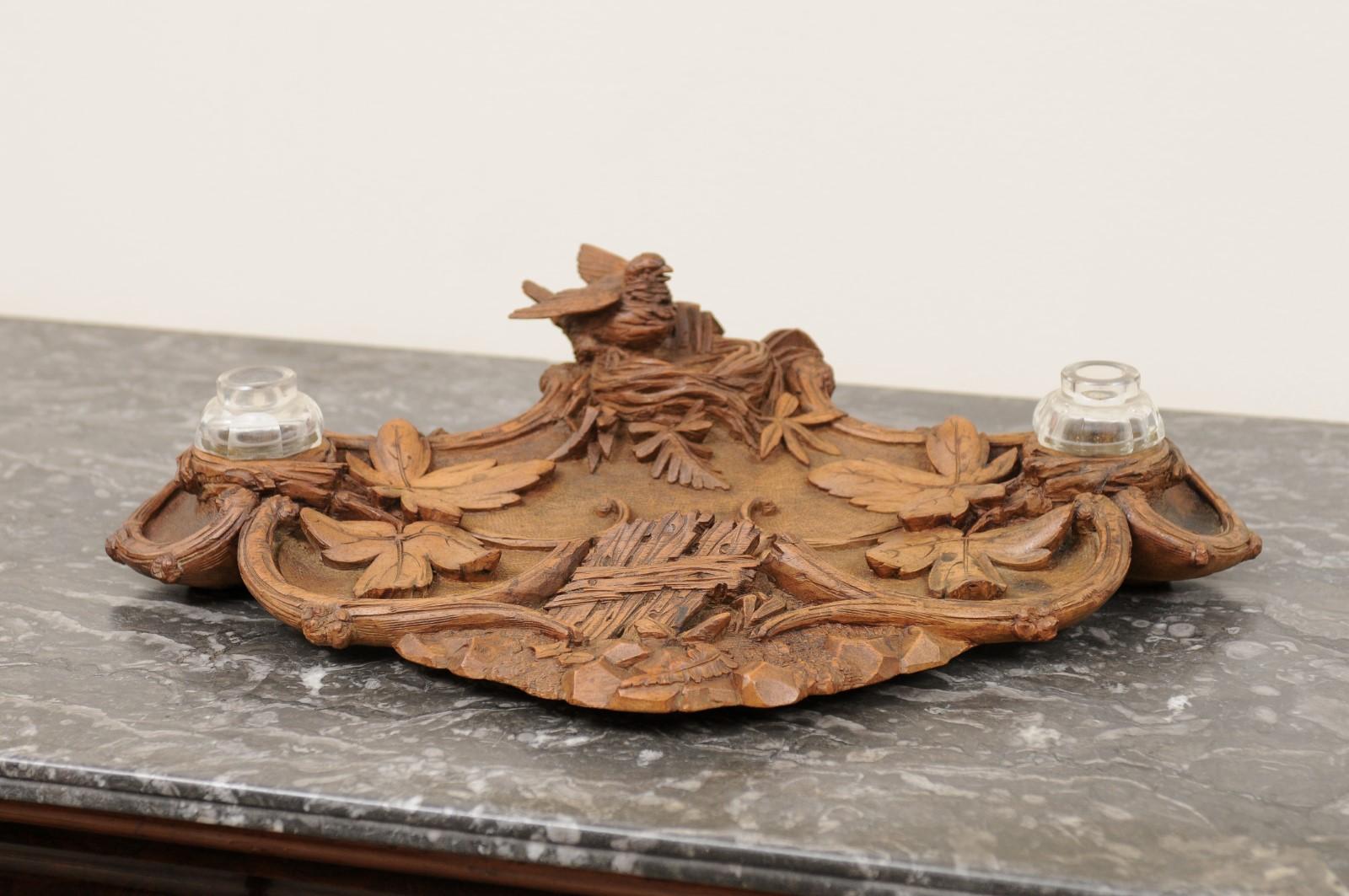 This lovely large carved Black Forest double inkwell is adorned with a bird on its nest on the top.
Acorn and oak leaves are the motif on the tray. It has a medium brown patina. A perfect compliment for a desktop or side table.