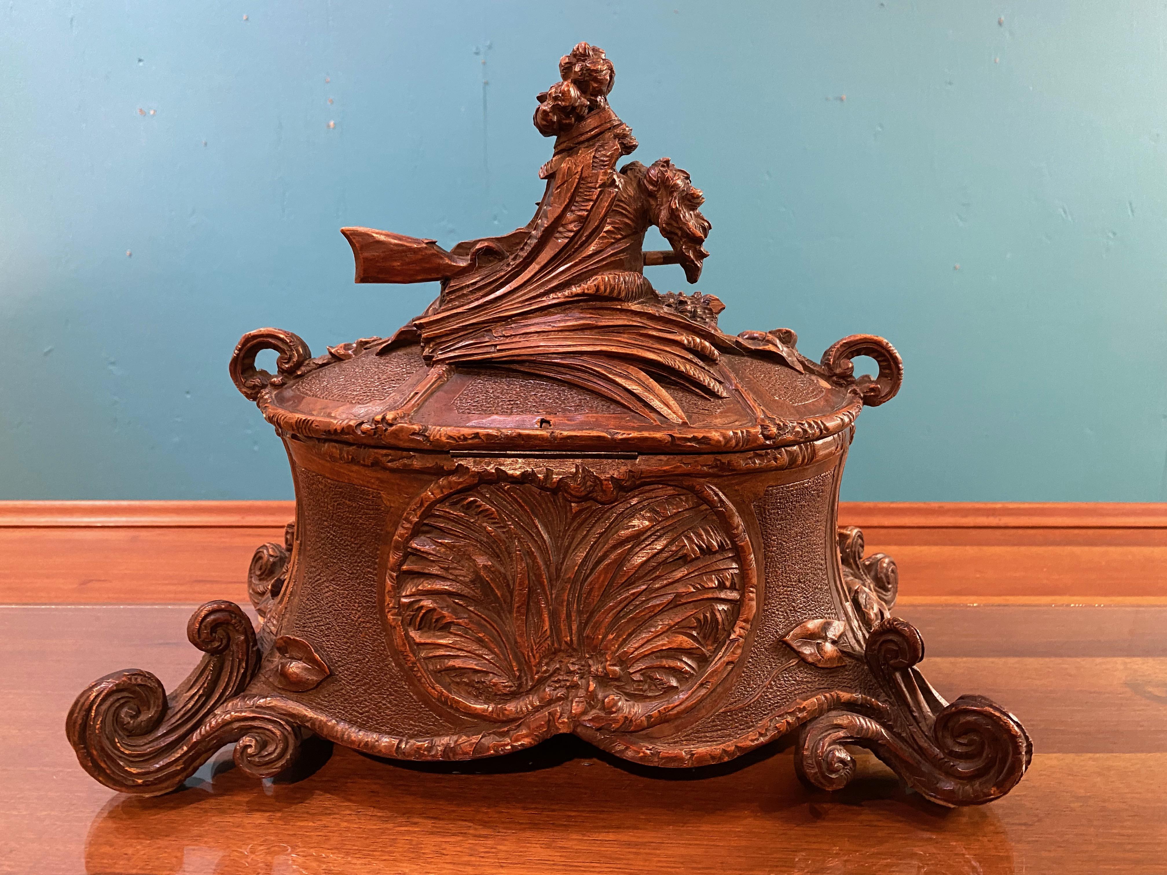 This jewelry casket or box is a superb example of 19th century, c. 1870, Black Forest carving. The box is finely detailed with carved wolf, wheat sheaves, and gun stock to the lid and a pair of hunting dogs, scrolling vines, and more wheat sheaves