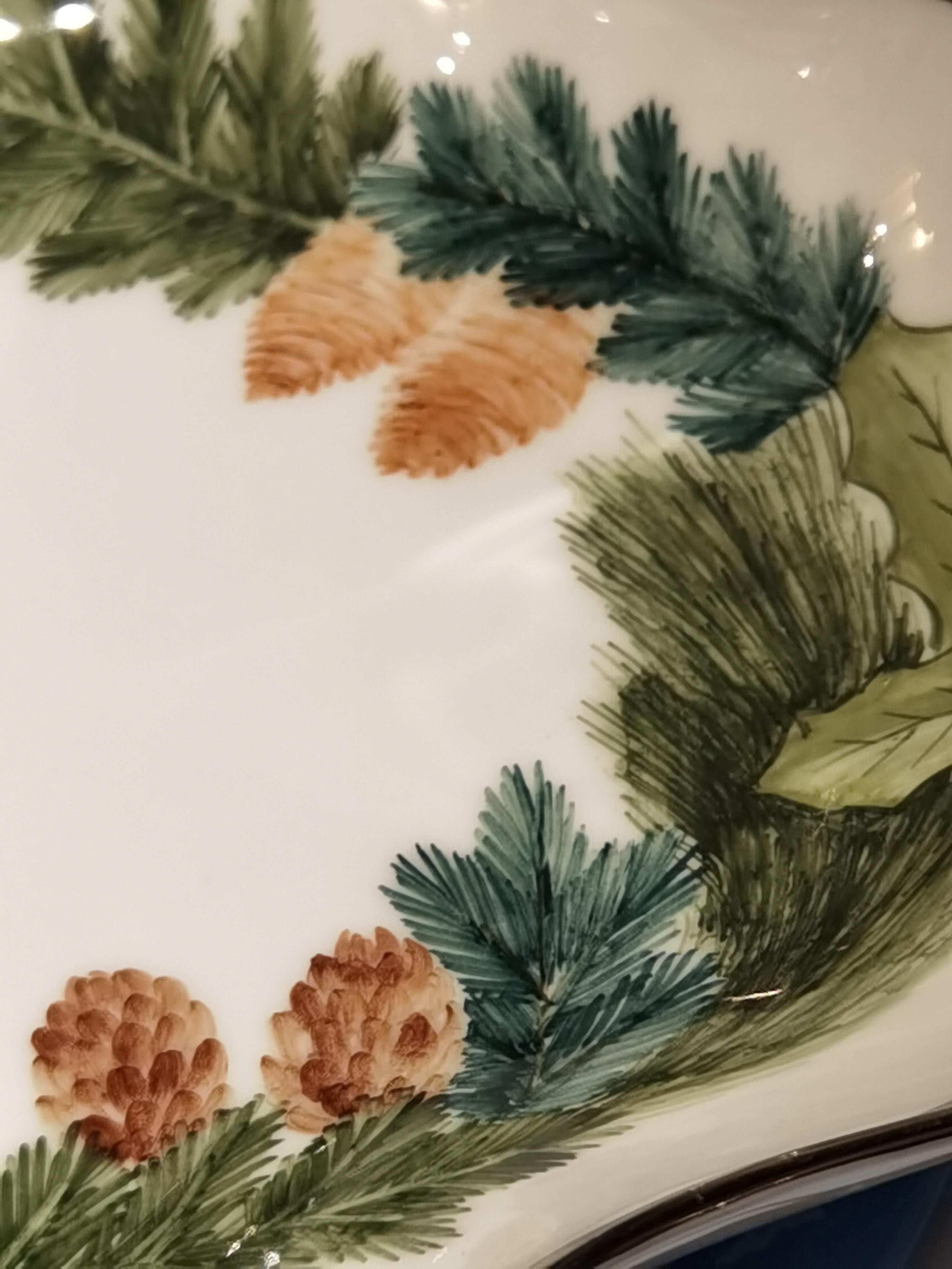 Plat en porcelaine peint à mains libres avec bord en platine. Peint dans un décor de Noël classique de forêt noire avec une guirlande verte de sapin et de pommes de pin. Entièrement fabriqué à la main en Bavière/Allemagne.