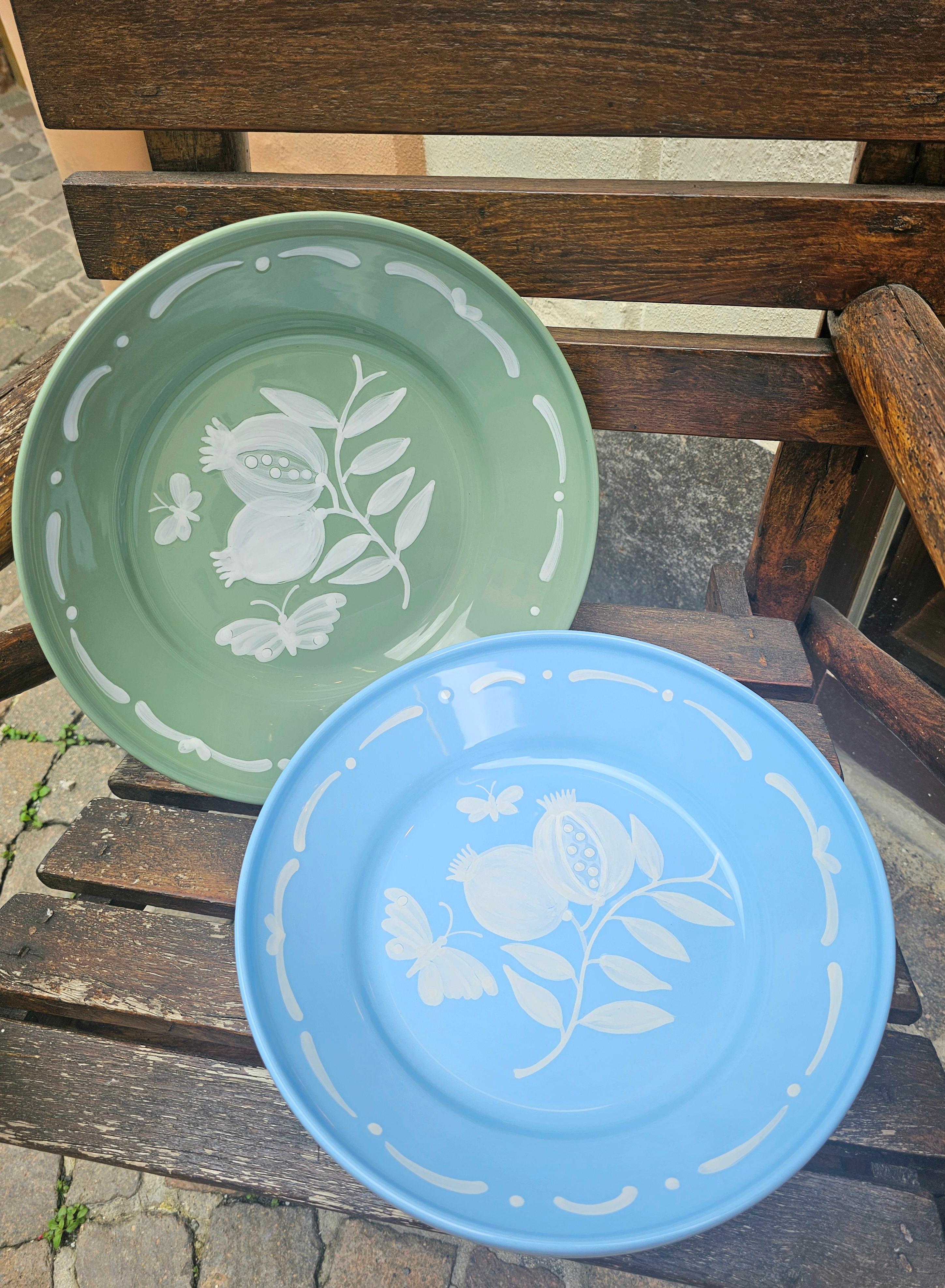 Large hands-free painted pottery dish in Country style. Glazed in ice blue and handsfree painting in white. The decor shows a hands-free painted pomegranate with butterflies and a hands-free painted garlande . 
Produced in Austria in the traditional
