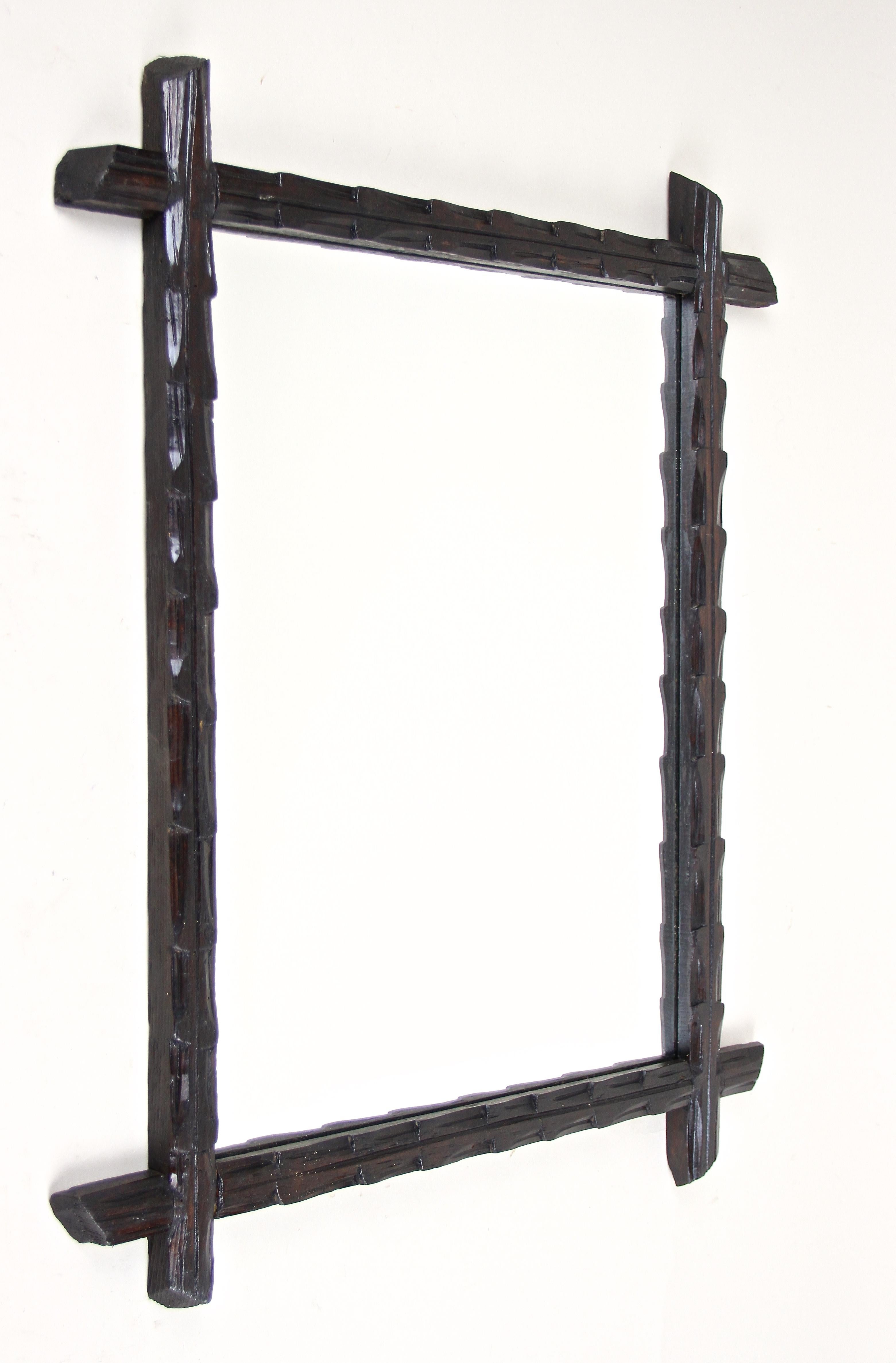 Uncommon rustic black forest wall mirror from Austria, around 1880. This antique wall mirror impresses with an unusual hand carved design, elaborately made out of basswood. A very dark brown almost black looking finish confers this great late 19th