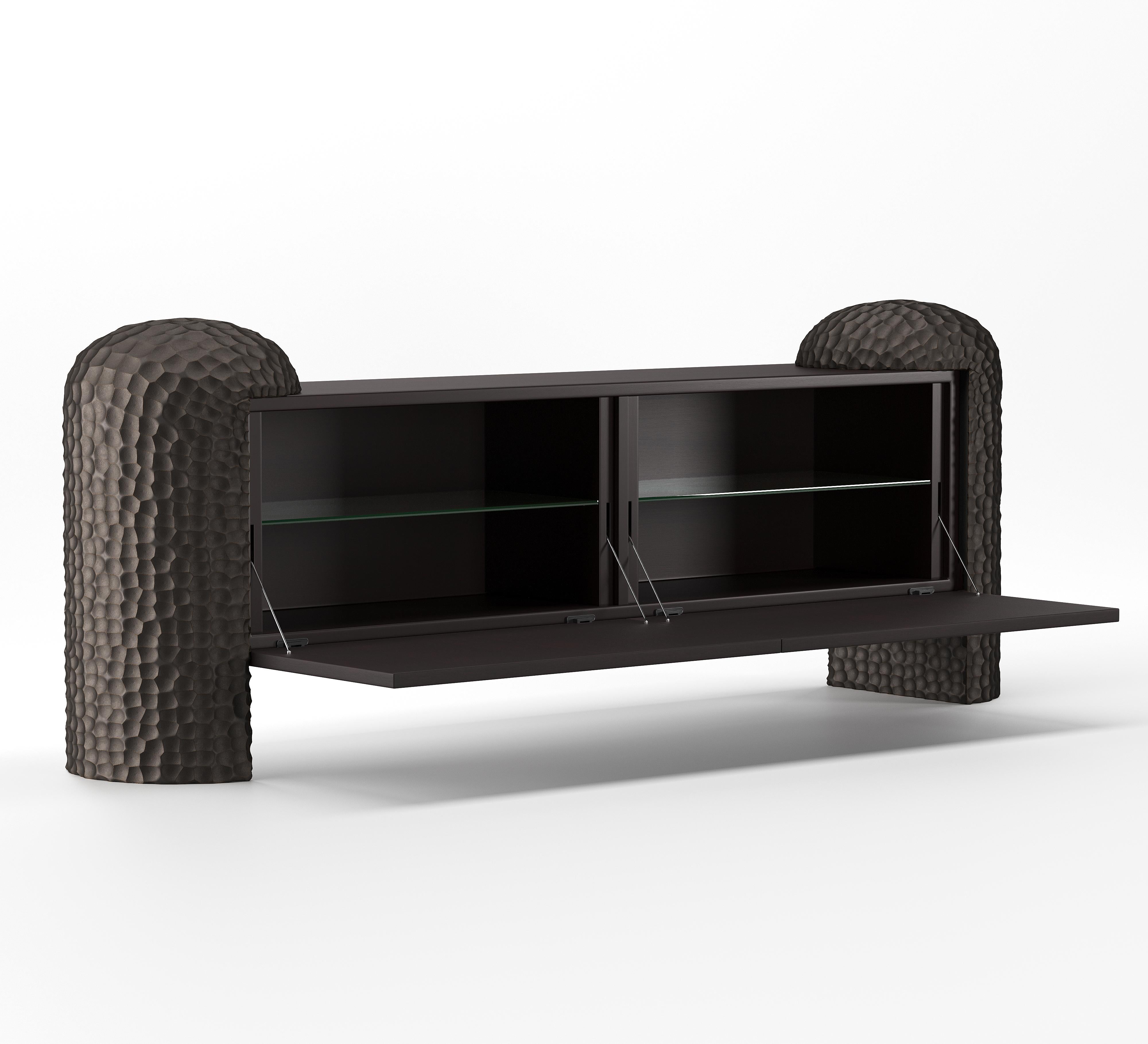 A sculptural statement piece rooted in nature, the Black Forest Sideboard is defined by its bold, hand-carved legs—monumental forms that evoke ancient tree trunks or forest columns. Between them, a minimalist body in wood veneer appears to float,