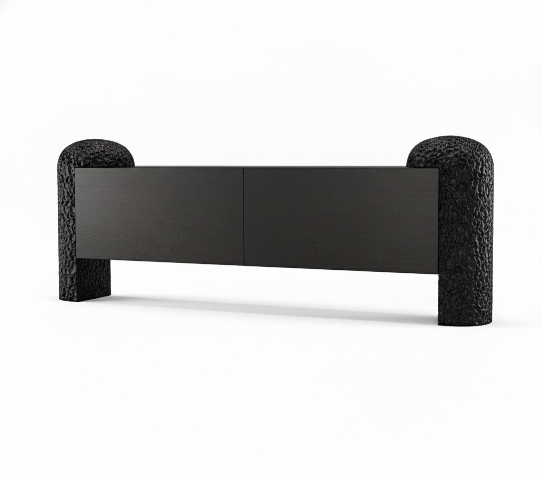 A sculptural statement piece rooted in nature, the Black Forest Sideboard is defined by its bold, hand-carved legs—monumental forms that evoke ancient tree trunks or forest columns. Between them, a minimalist body in wood veneer appears to float,