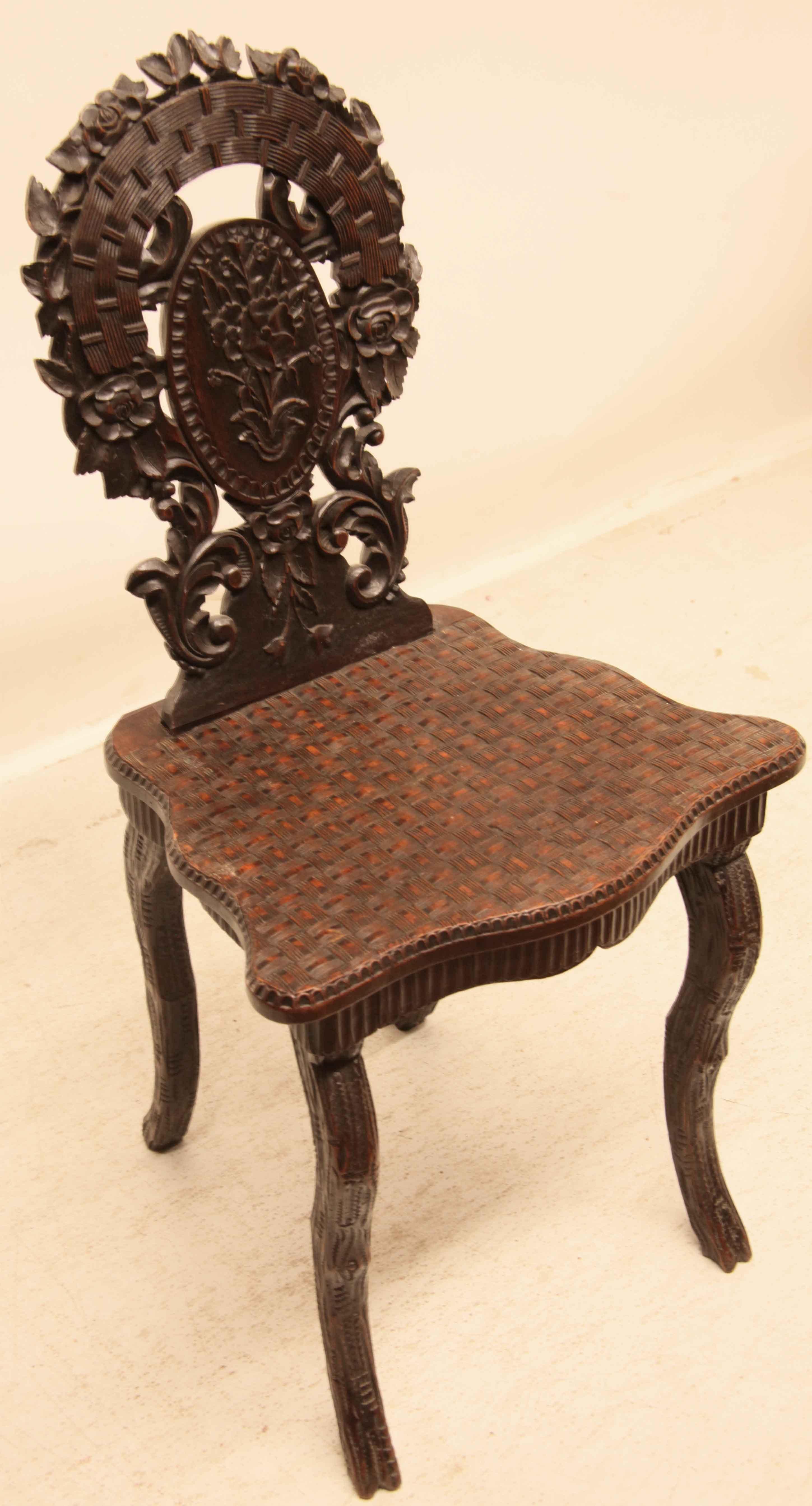 Black Forest side chair,  the back featuring carved flowers, foliage and central oval medallion. The seat has serpentine shaped sides and front with a carved basket weave design;  below this is a reeded apron .  The front and back legs have a