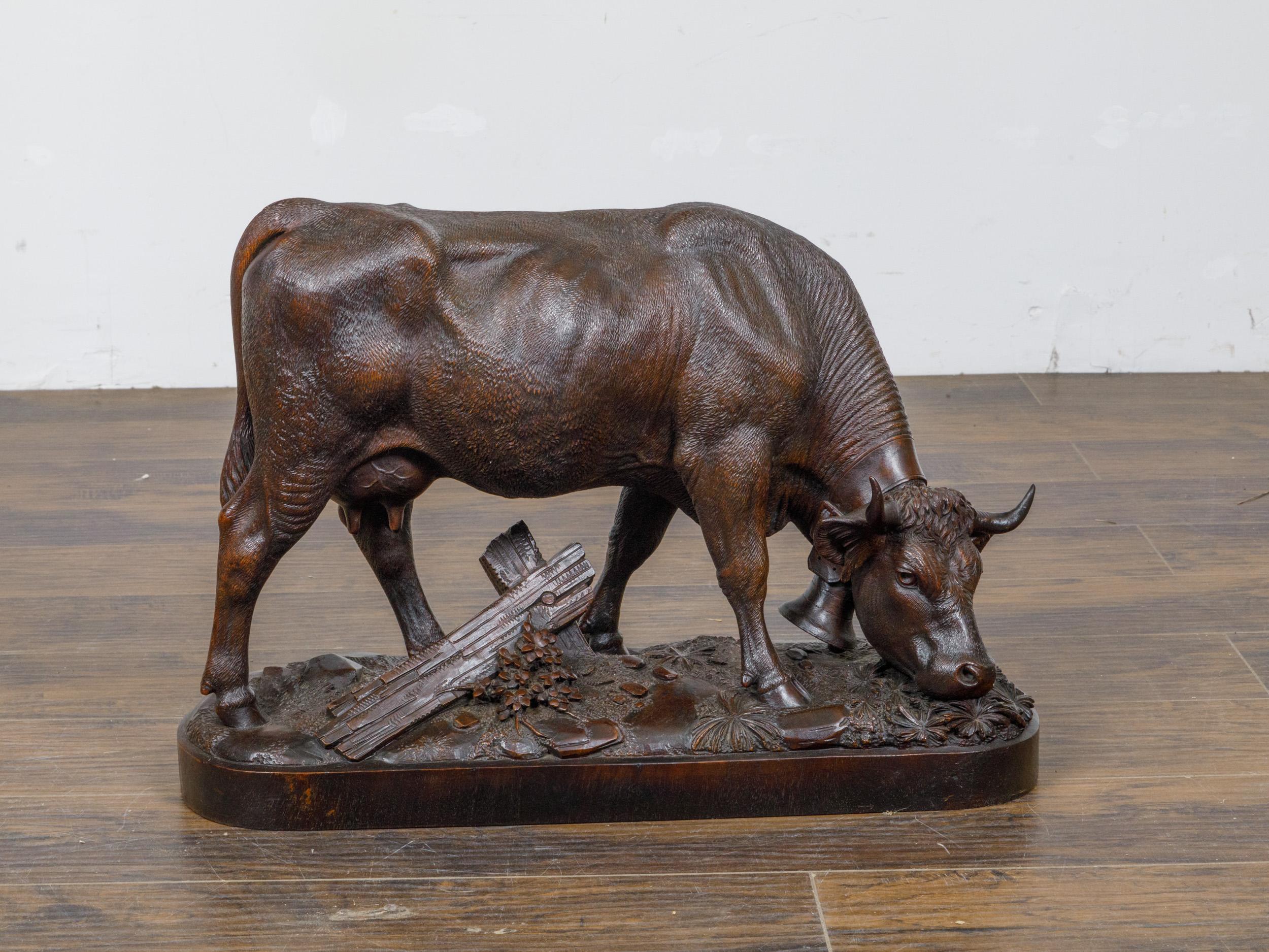 A Black Forest Swiss hand-carved wooden cow from circa 1880. This exquisitely hand-carved wooden cow is a pristine example of Black Forest artistry from circa 1880, originating from Switzerland. The sculpture depicts a grazing cow, its head