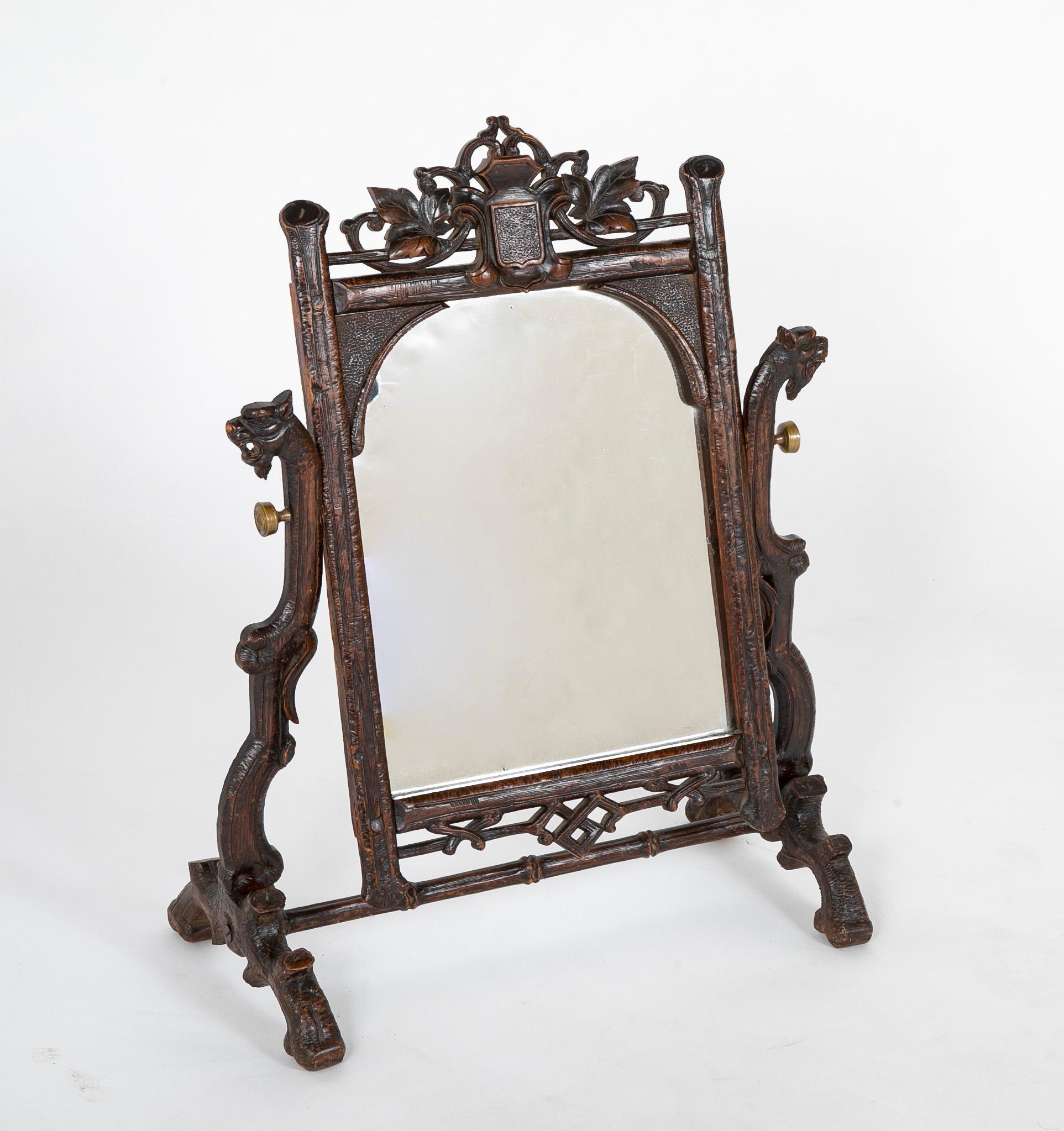 A rare Black Forest vanity / dressing mirror with gargoyle supports having naturalistic tree branch motif and elaborately carved oak leaves. Swivel mirror.