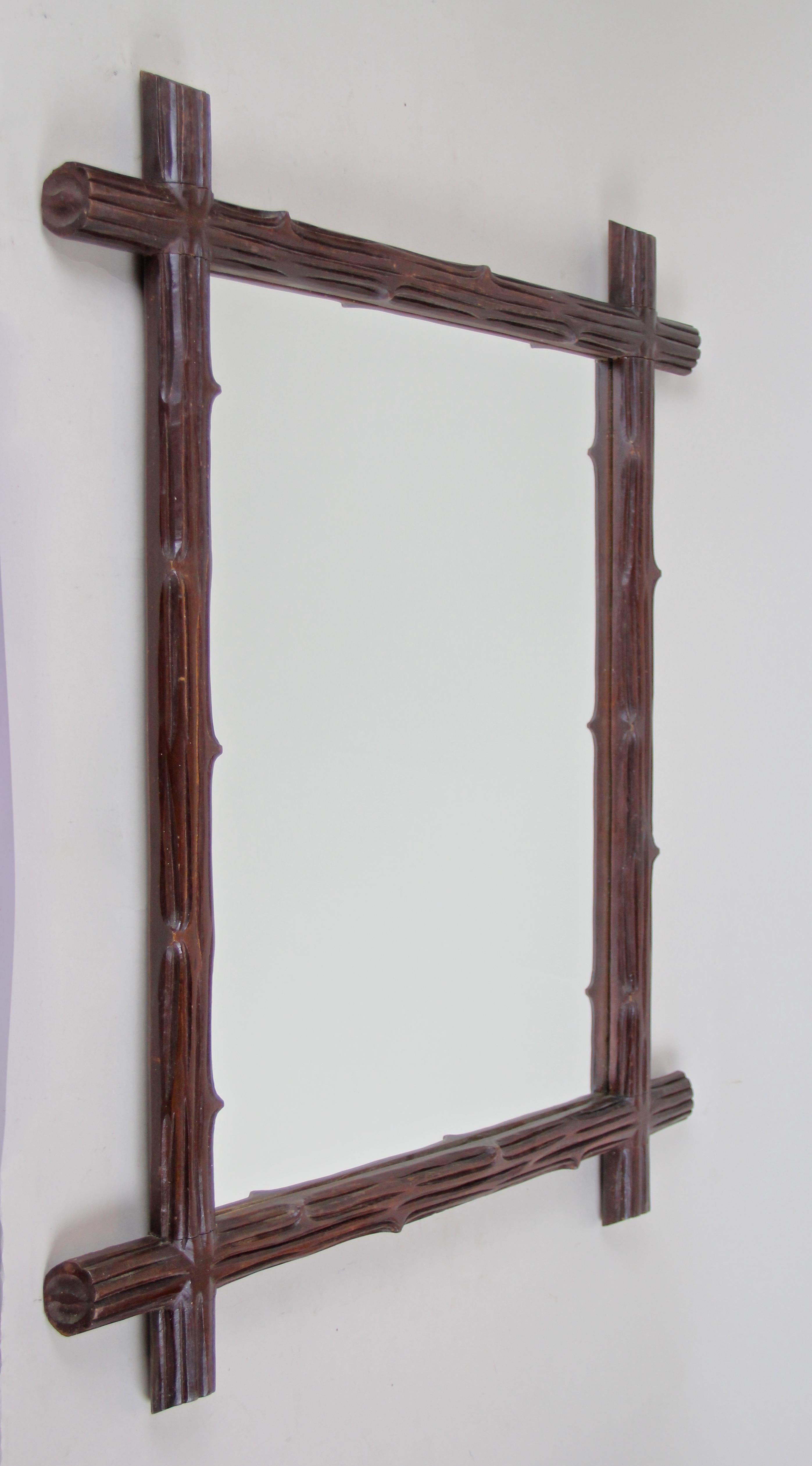 From circa 1900, the turn of the century in Austria comes this beautiful wooden Black Forest wall mirror. A simple but elegant design was created out of hand carved basswood, showing the typical 