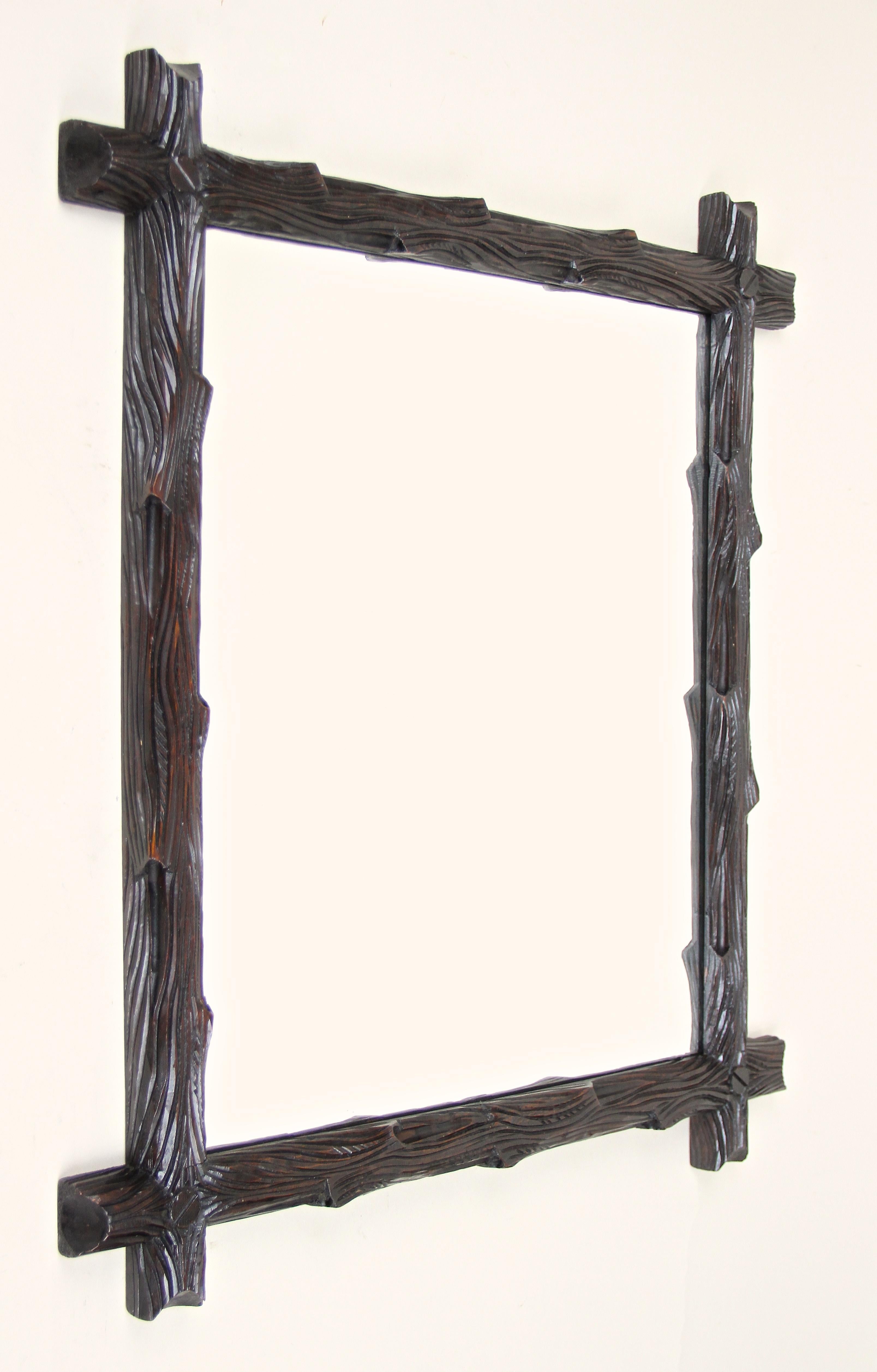 Outstanding Black Forest wall mirror out of Austria from circa 1880. This rustic style wooden mirror has been elaborately processed out of basswood and impresses with its artfully carved frame in the manner of tree branches. The beautiful darkbrown