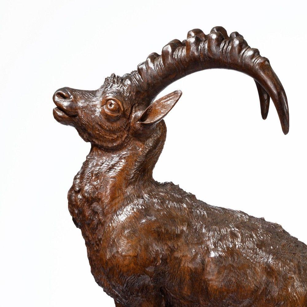 An imposing ‘Black Forest’ wood carving of an Ibex, 
standing on a rocky outcrop with realistically carved ribbed antlers and rippling fur.