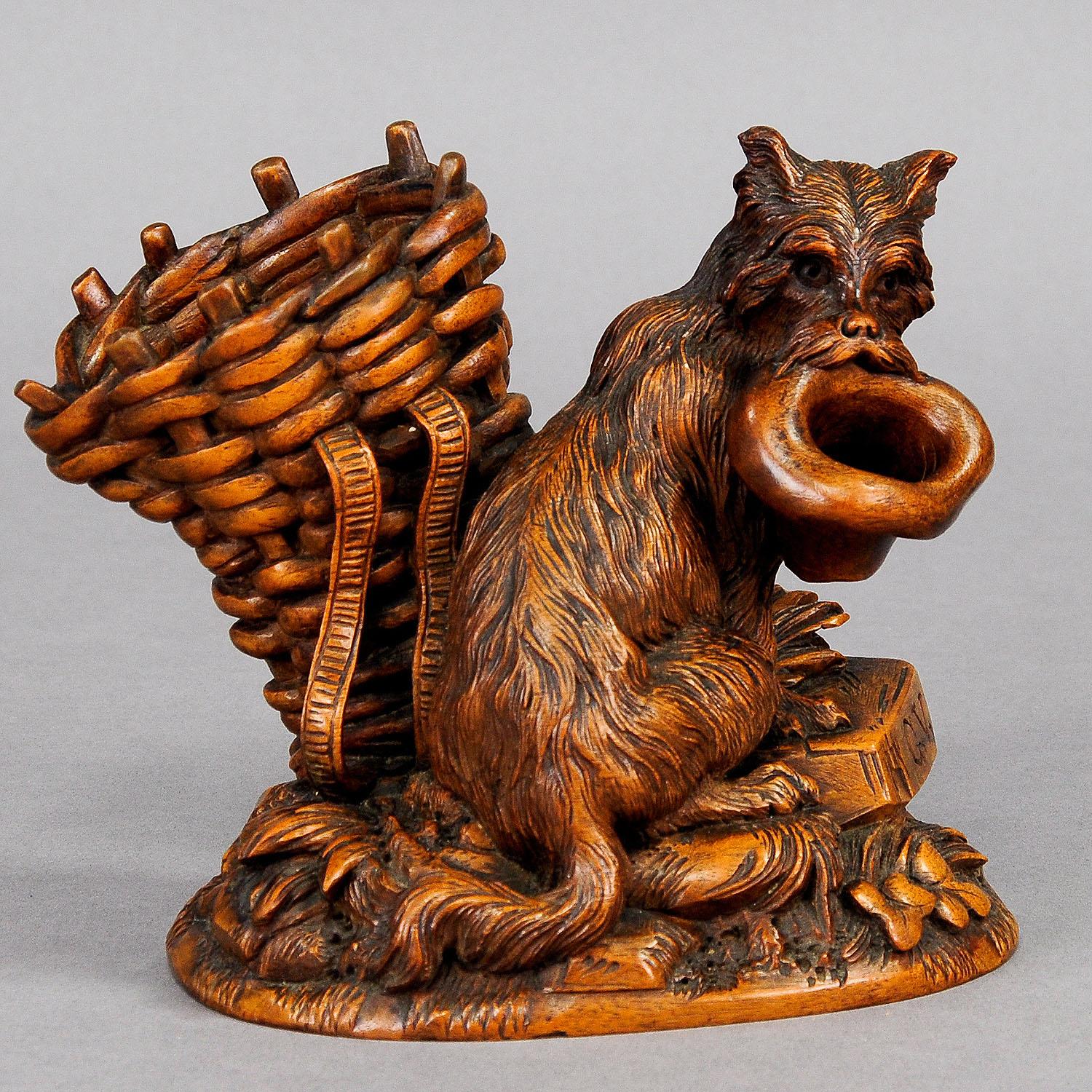 A whimsical Swiss wood carving. A long hair terrier is begging with his masters hat beside a basket. Handcarved ca. 1900 in Switzerland in the area of Brienz. Signed: G. V. This great black forest carved sculpture would be a stunning addition to any