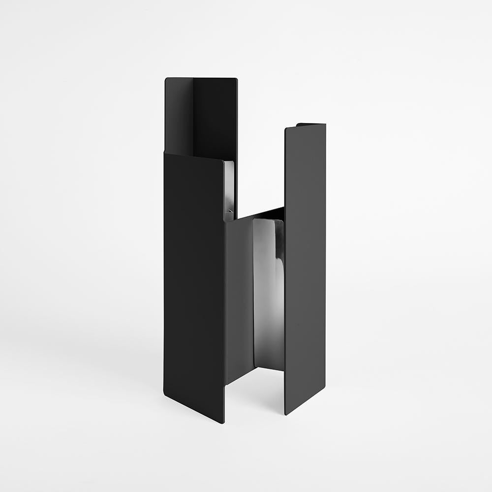 Black fugit vase by Mason Editions
Design: Matteo Fiorini
Dimensions: 12 × 15 × 34 cm
Materials: Iron, pirex glass.

Fugit vase consists of a metal sheet that seems to turn and close around itself, generating an alternation of fullness and