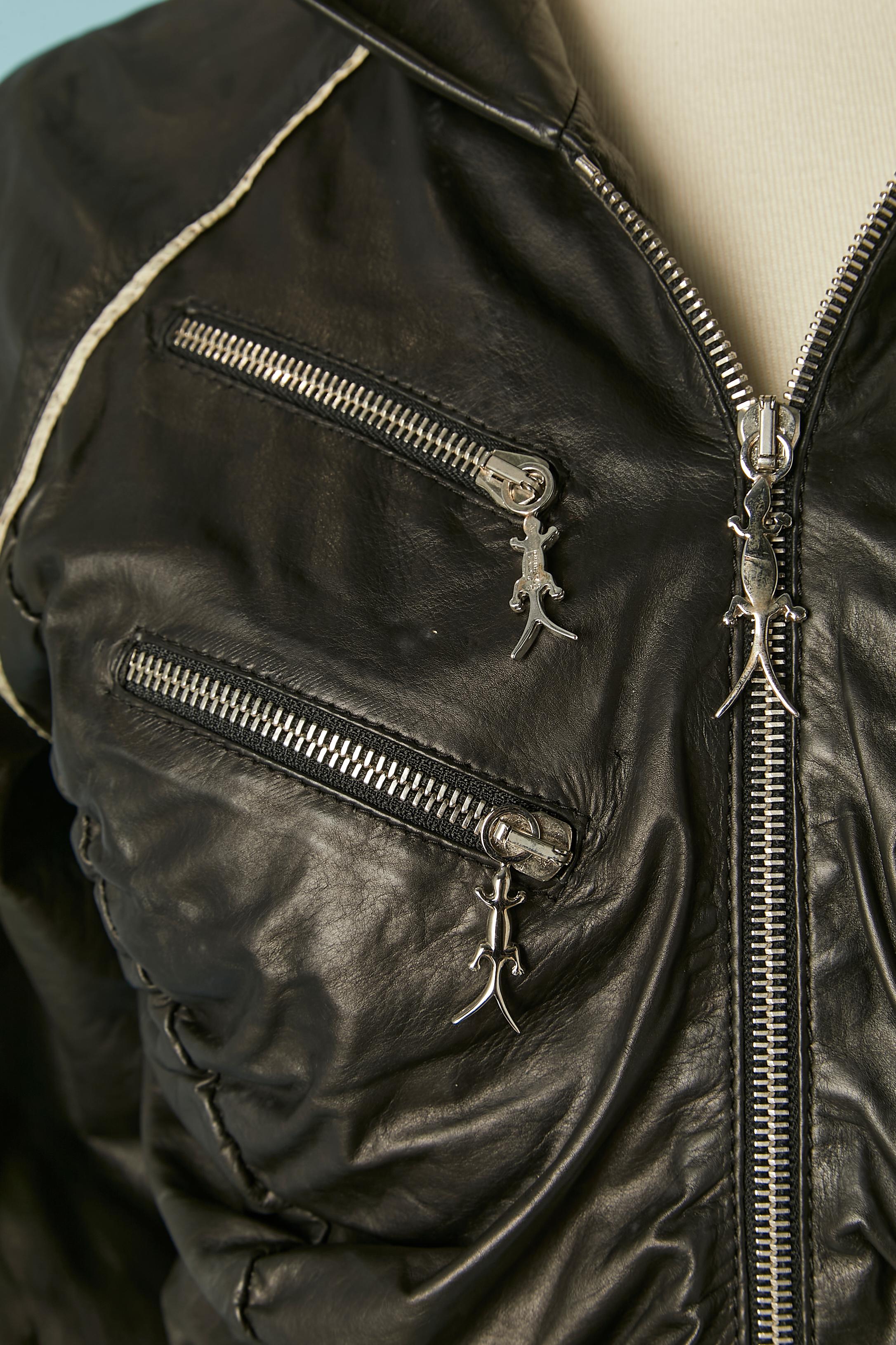 Black genuine leather jacket with hood. Black chiffon lining. 
Pocket with zip closure and zip closure in the middle front . Silver metal lizard zip puller. Draped on the side front and side back. Leather ribs on the bottom edge and sleeve edge