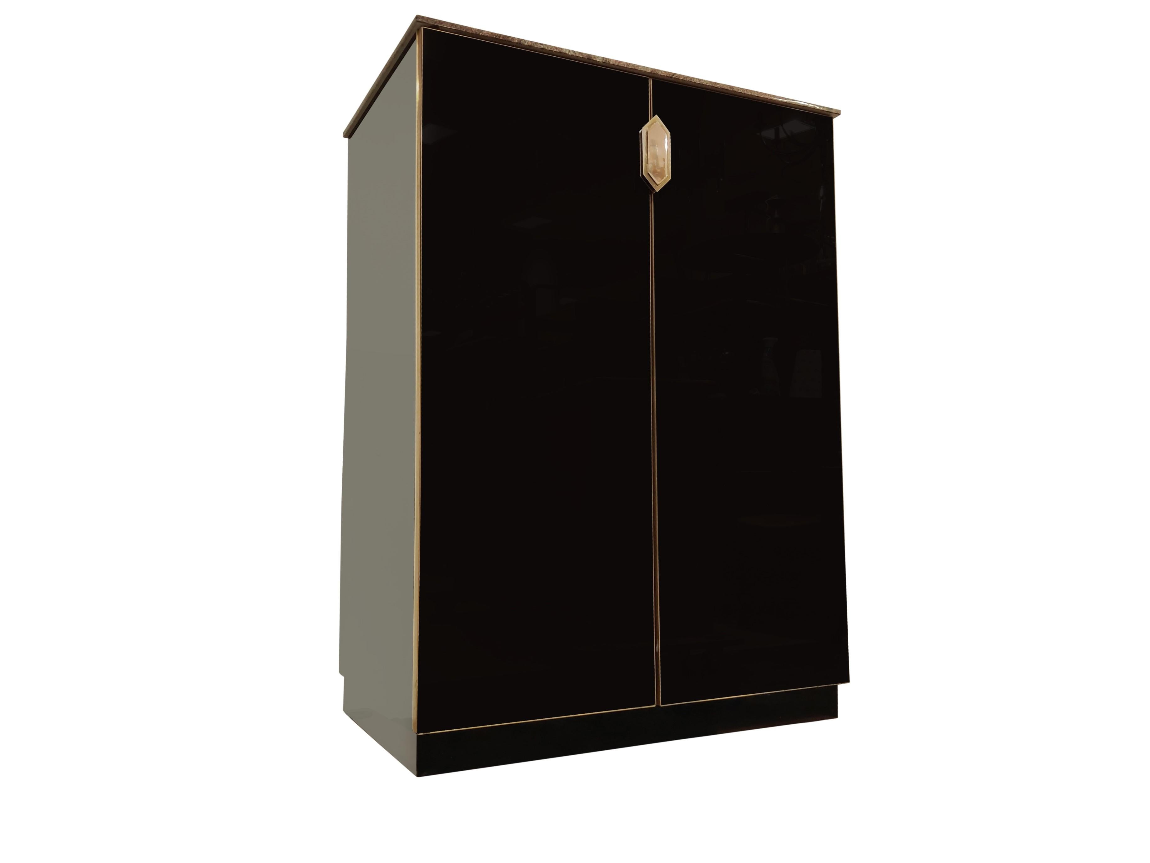 Mueble bar Hollywood Regency de cristal negro y latón con una preciosa encimera de piedra de granito.

Tiene 2 puertas con un bonito tirador y dos estantes: mucho espacio para guardar vasos y botellas. 

Estas piezas dan un gran toque de glamour