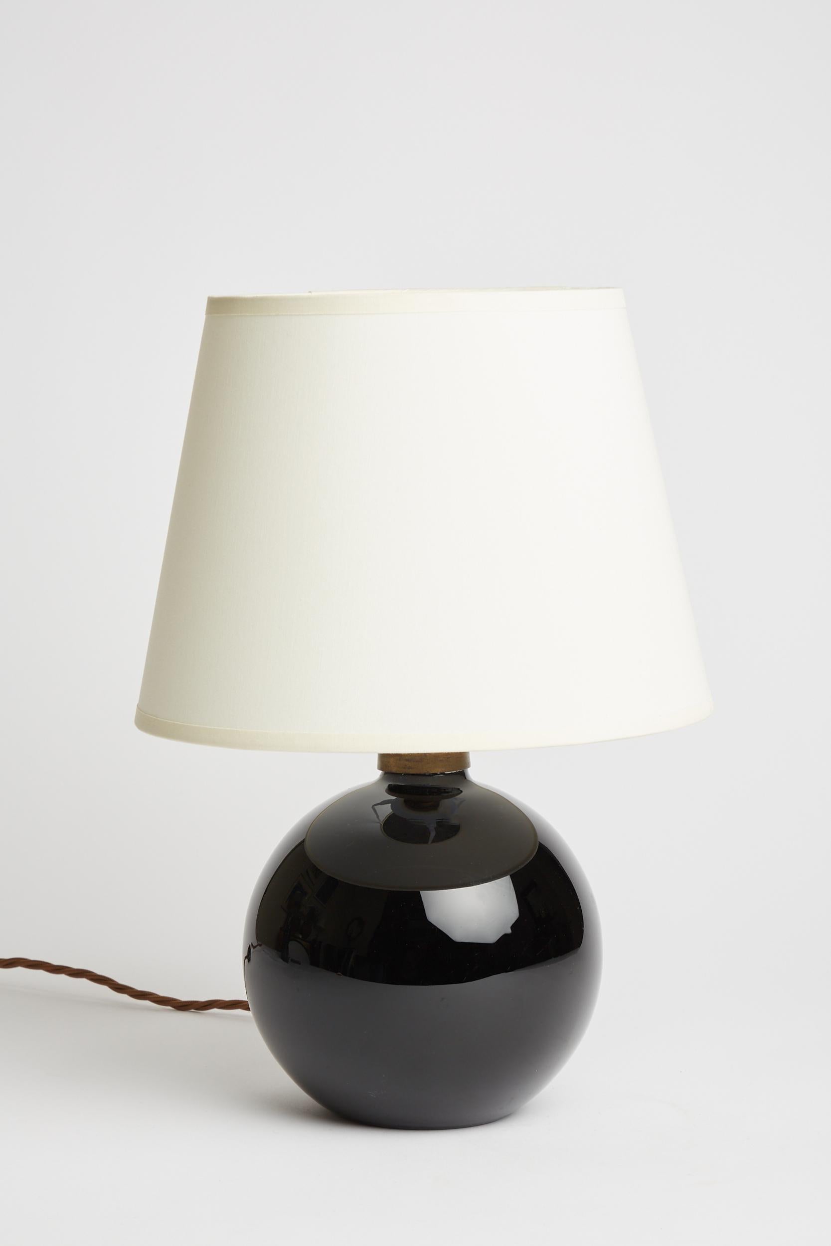 A black opaline glass table lamp by Jacques Adnet (1900-1984).
France, Circa 1930.
With the shade: 36 cm high by 25 cm diameter.
Lamp base only: 22 cm high ny 16 cm diameter.