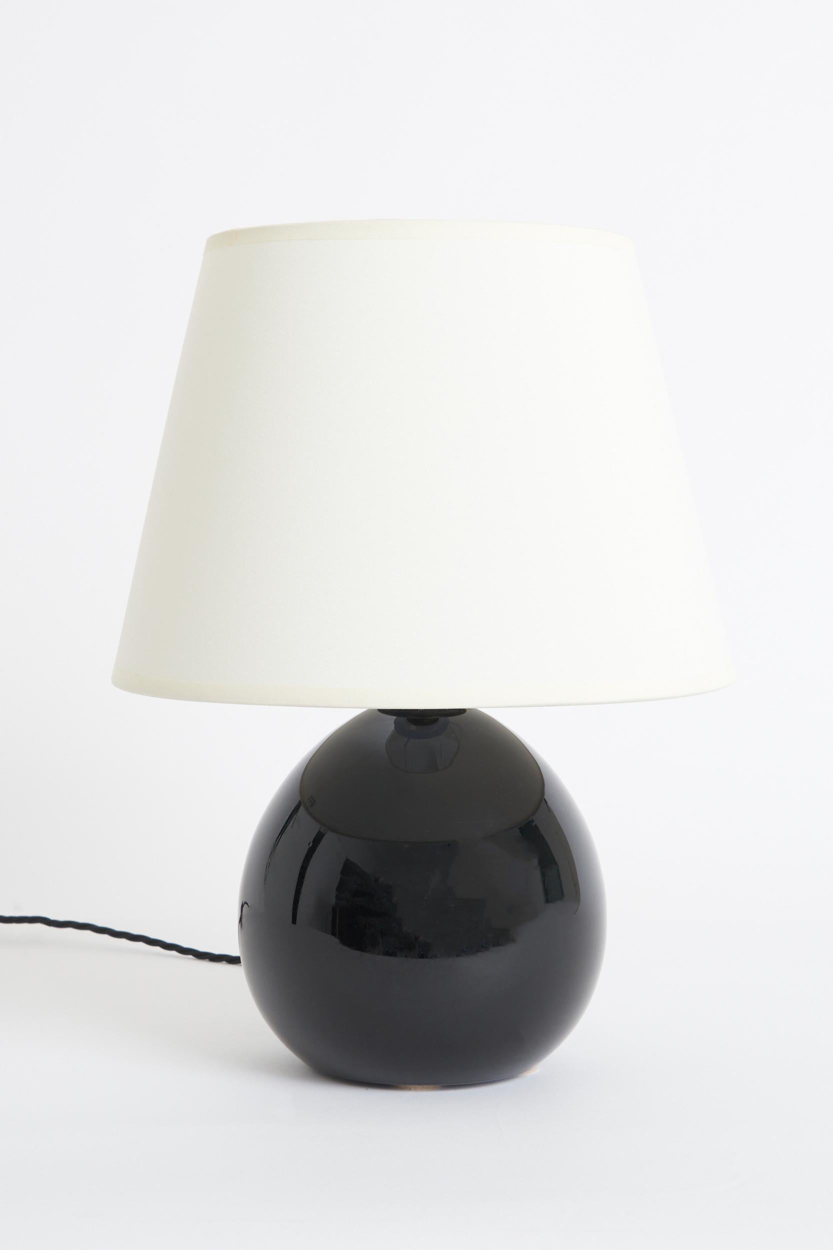 An Art Deco black opaline glass table lamp, probably by Jacques Adnet (1900-1984).
France, Circa 1930
With the shade: 41 cm high by 30.5 cm diameter
Lamp base only: 24.5 cm high by 18 cm diameter