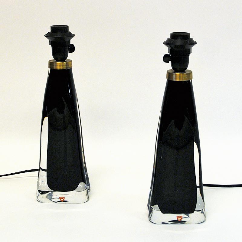 Lovely midcentury pair of black glass table lamps model RD1323 designed by Carl Fagerlund for Orrefors Glass, Sweden, 1960s. Inner black crystal glass core surrounded by a clear glass cover. Brass details on top. The lamps are heavy with elegant