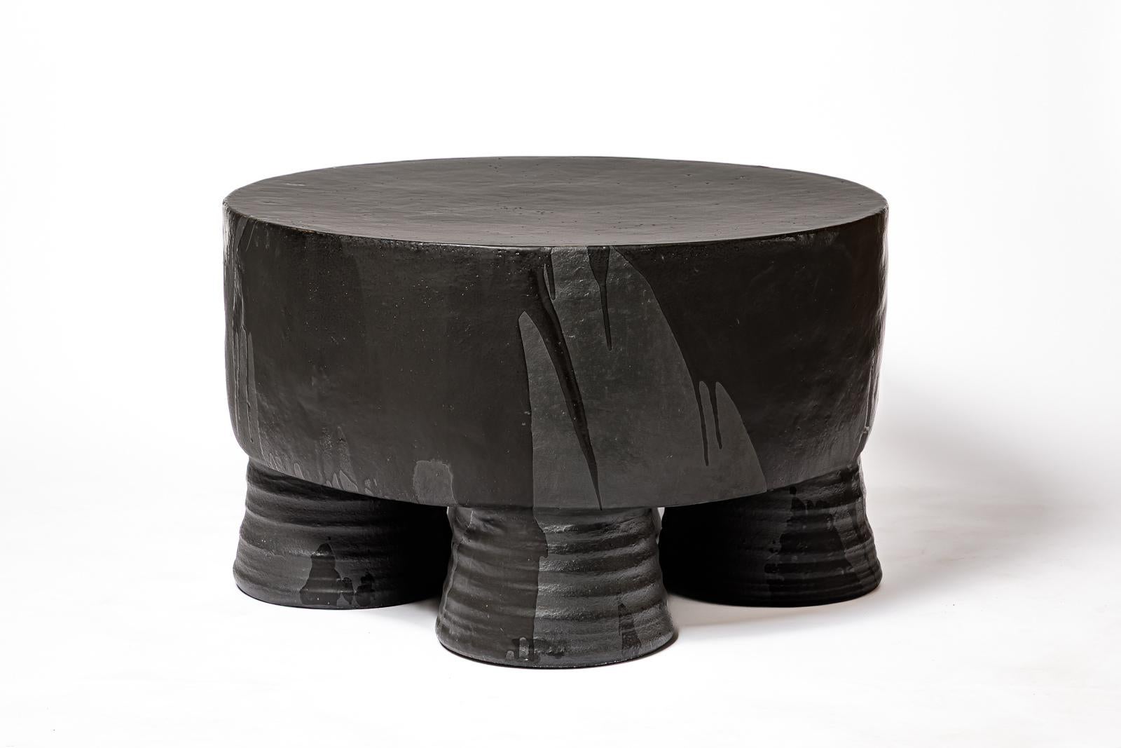 Tavolino in ceramica smaltata nera, opaca e lucida di Mia Jensen. 
Firma dell'artista sotto la base. 2025.
H. : 17,7 x 29,5 pollici.