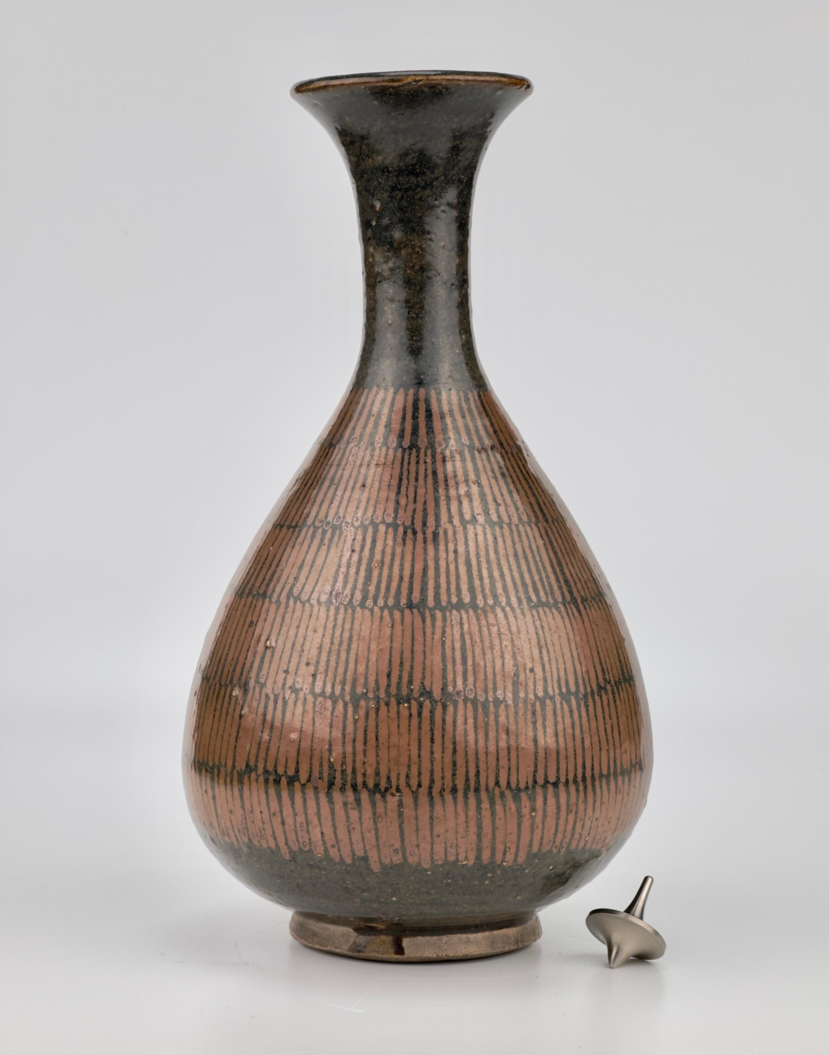 Of broad pear shape rising from a low foot to a waisted neck and flared rim, covered overall with a lustrous brownish-black glaze with rare six bands of russet-strokes radiating in yuhuchunping shape.


Period : Northern Song-Jin Dynasty
Type :