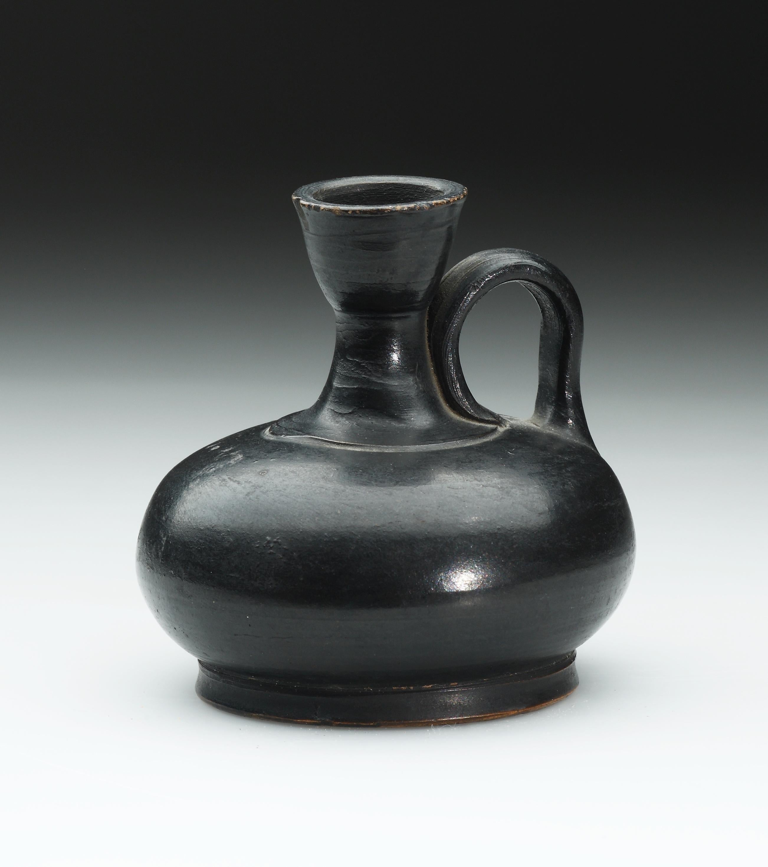 Attic second half of the 5th century B.C

Clay, black glaze. Measures: H. 7.8 cm

A squat, globular vessel on a low ring foot, with funnel-shaped mouth, and a single high-slung handle attached to short neck and shoulder. Offset at join of neck