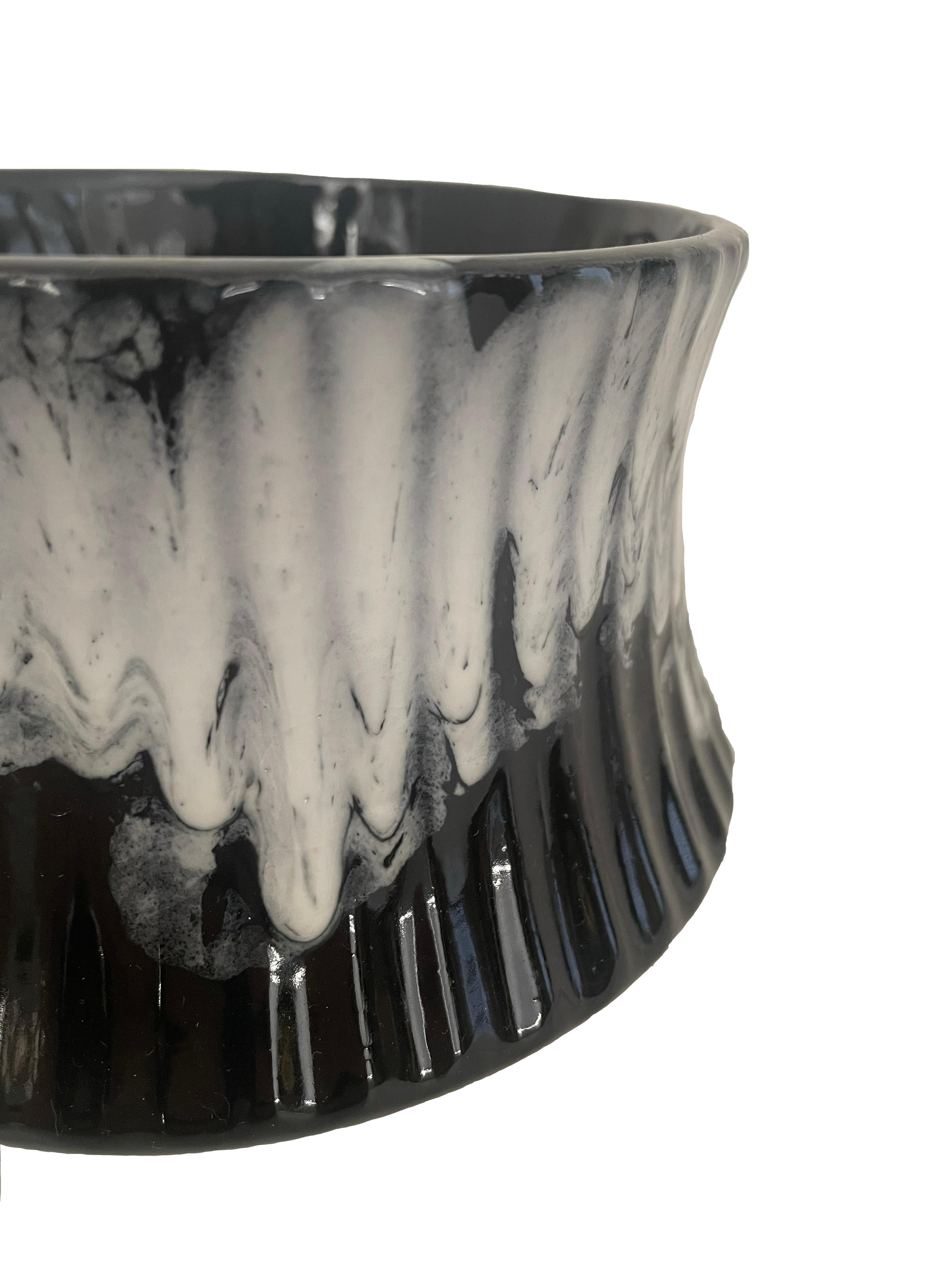 Hollywood Regency style glazed stoneware planter. Wheel-thrown, formed with fluted lip and vertical ribbing exterior detail. Black, high-gloss base with dripped glaze in a creamy-grey tone. Variation in glaze saturation throughout. The interior is