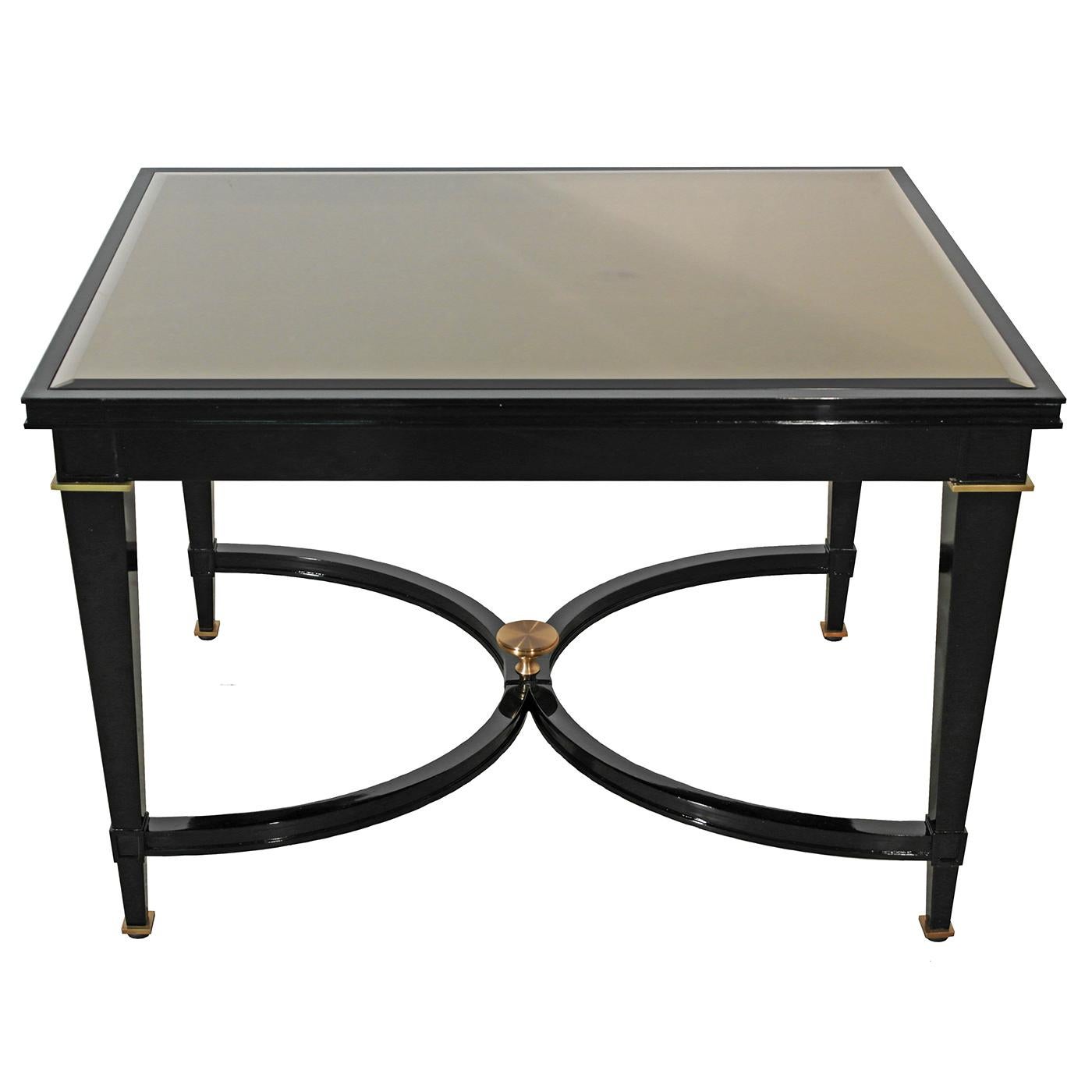 This elegant side table is crafted from solid wood, boasting a glossy black lacquered finish. Featuring tapered legs and two semi-circular base details, the design is enhanced with brass accents, characterized by a light brushed bronze finish.