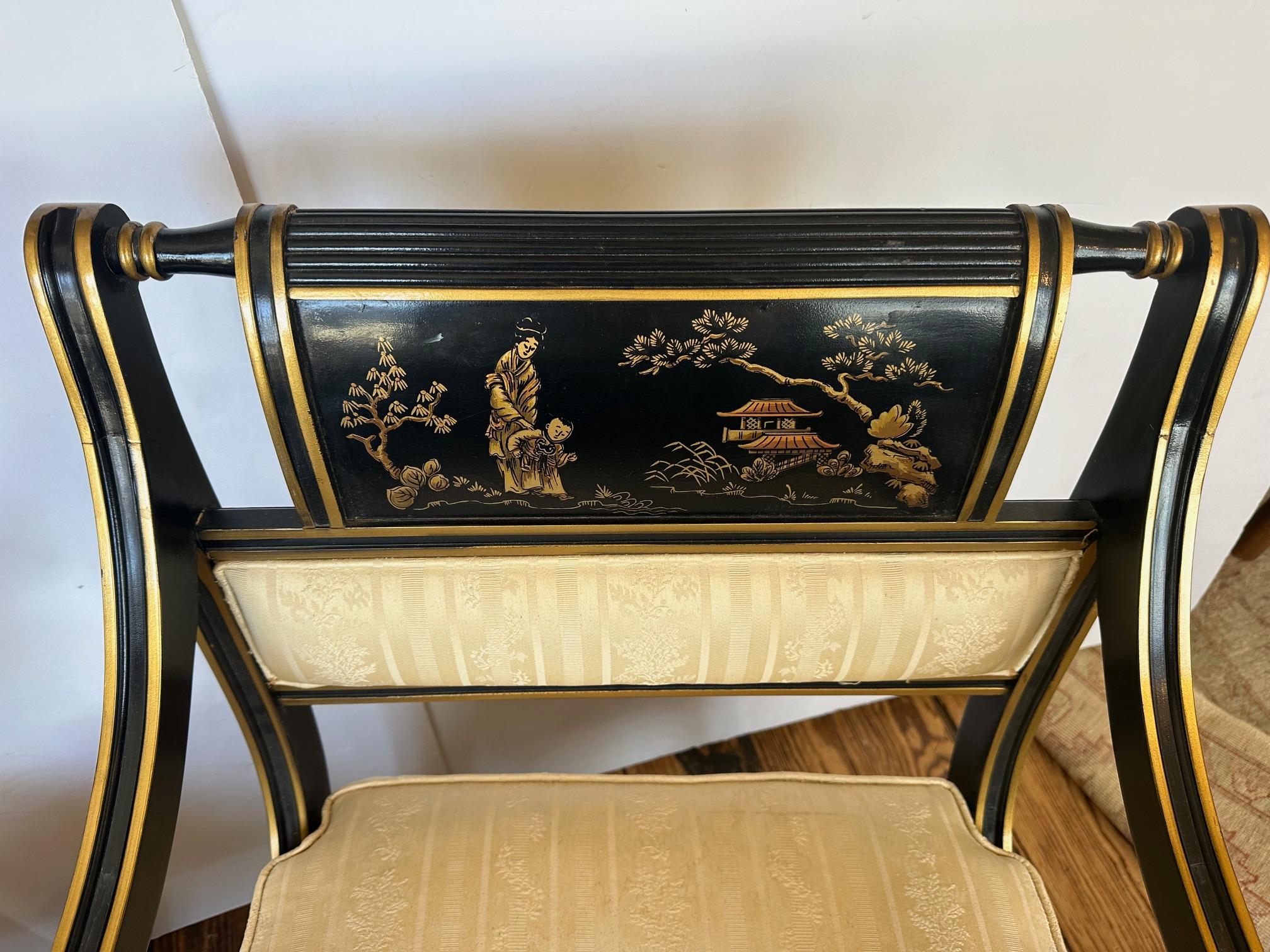 Elegante paire de fauteuils décorés de Chinoiserie, à fond noir avec des motifs figuratifs or et rouge.  Le siège est rembourré et devrait être refait.