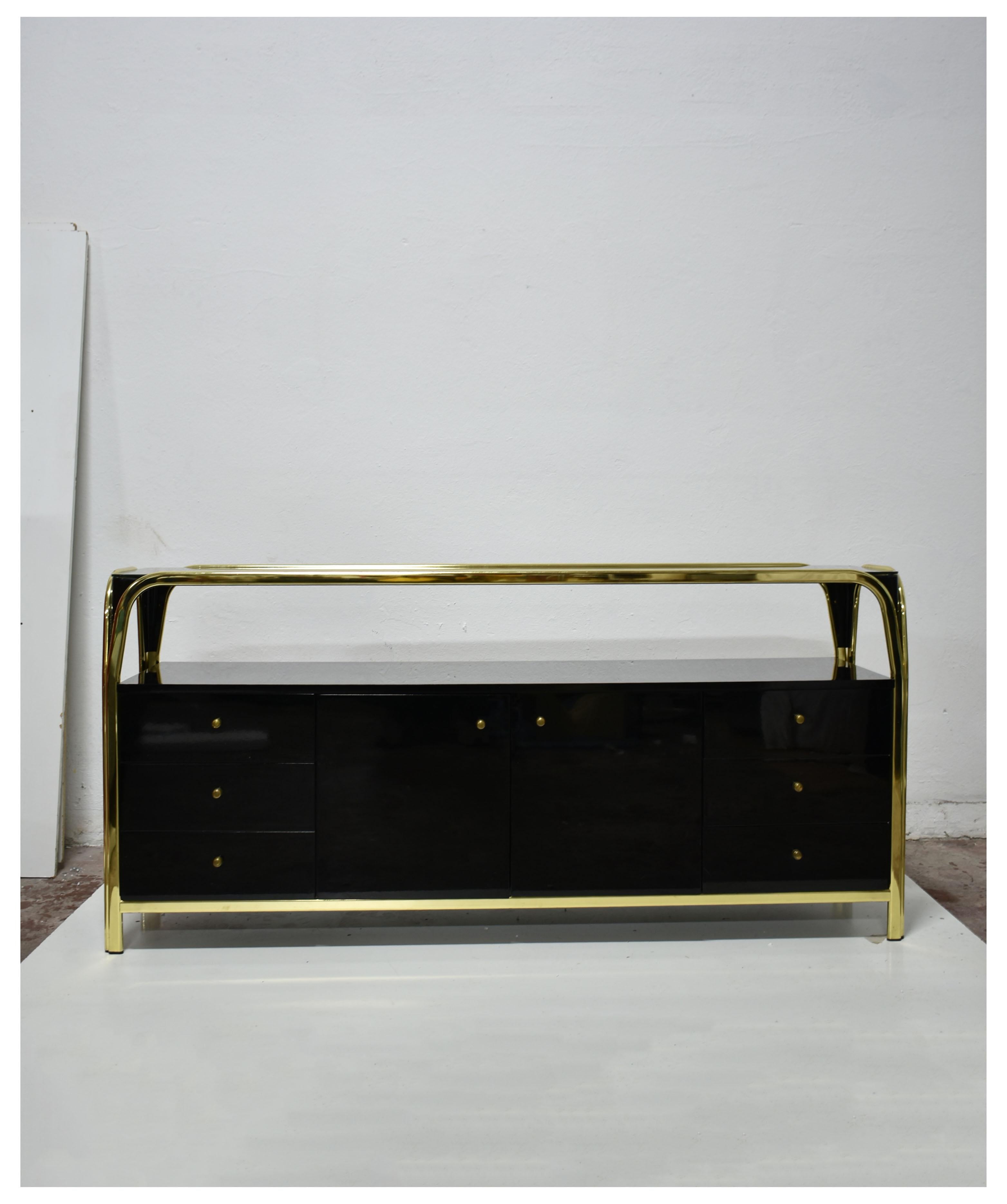Italian mid-century sideboard from an unknown designer and manufacturer.

The sideboard features a brass plated metal frame and storage made of black lacquered wood with a shiny finish, storage is divided into 3 units. The central unit has two