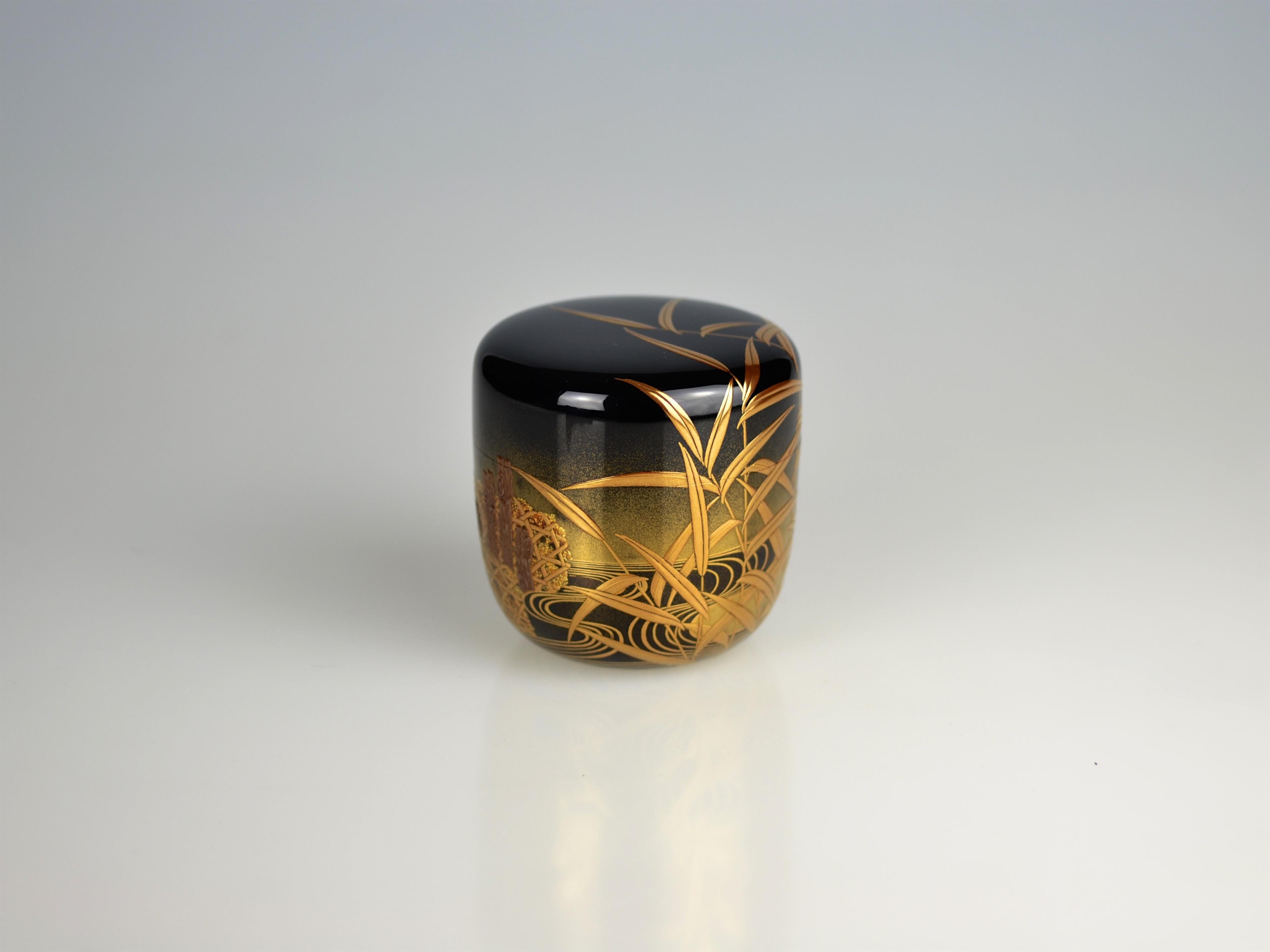Fantastic maki-e tea caddy with a river scene showing reed and traditional stone baskets (Jap. jakago) in takamaki-e on a polished black lacquer ground with fading nashiji decoration (Jap. togidashi-e). The skillful use of golden applications and