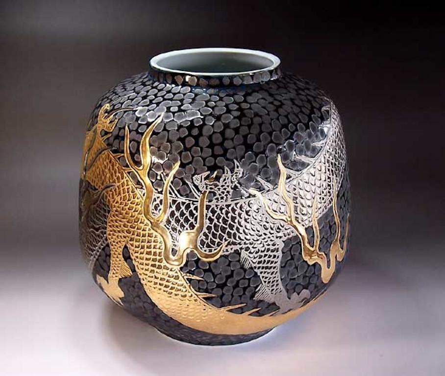 Exquisite contemporary large porcelain vase, hand painted showcasing a dramatic scene of two dragons facing each other set against a dimpled black background, a signed piece from the signature dragon collection by highly acclaimed award-winning