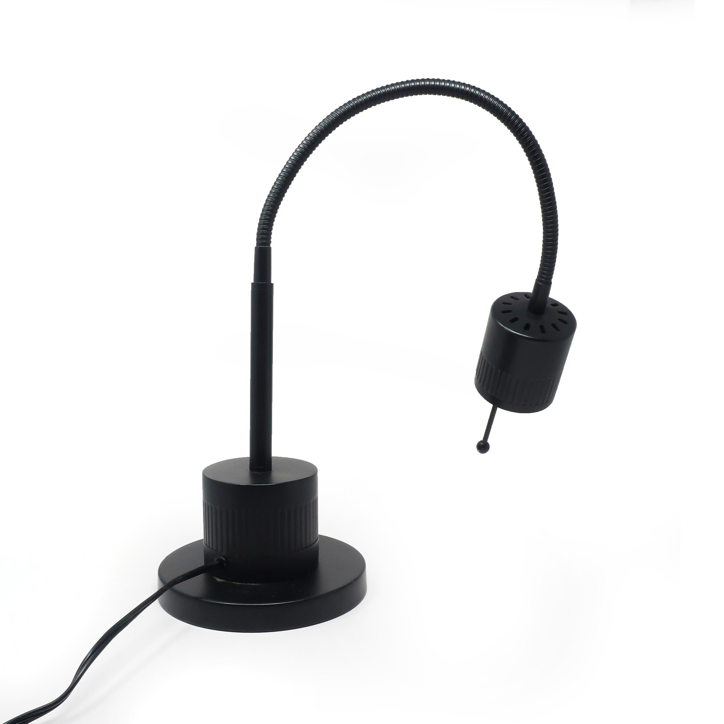 A Tensor gooseneck desk lamp that is perfect for a minimalist or 1980s inspired home or office. Round black metal base, gooseneck stem, shade with halogen lamp, and on/off switch on the shade. In good condition with a few small marks consistent with