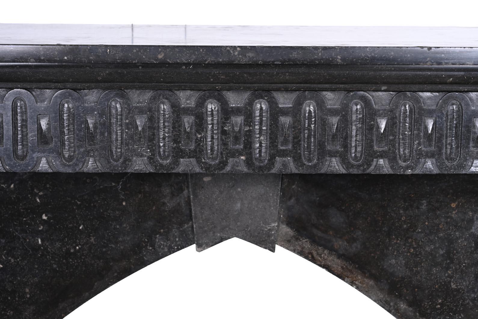 Caminetto architettonico scolpito in granito nero, con due montanti monumentali a forma di figure maschili classiche. Ognuno di loro indossa un elmo e si trova in cima a un basamento scolpito con i piedi nudi. I torsi sono ornati da ghirlande a