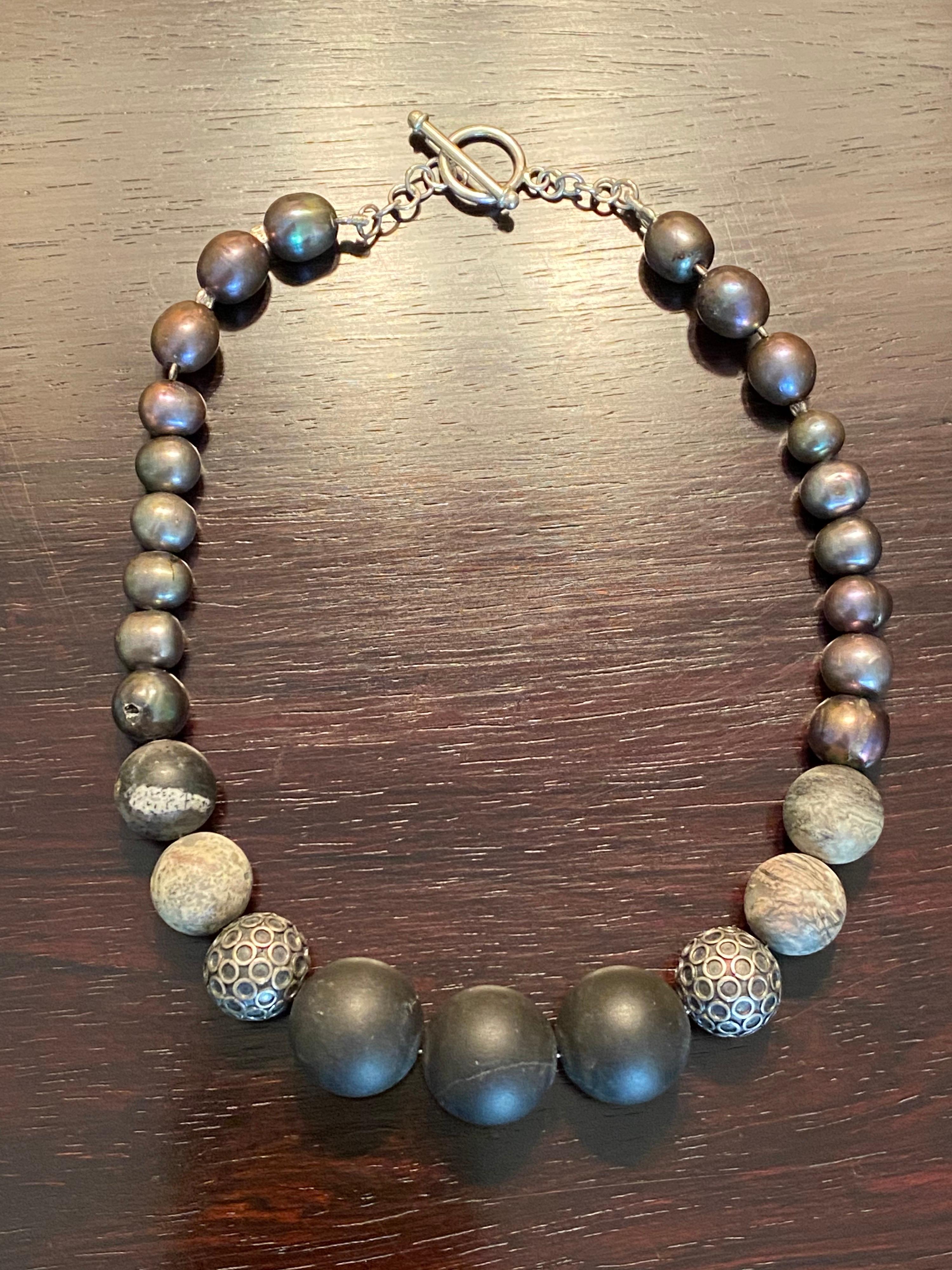 Tiny neck? Great, this is the necklace for you. Very fashionable and on-trend. Has 18 Freshwater silver and gray cultured pearls with large Black Onyx Beads and Marbled Jasper Beads with a Sterling Silver Toggle Clasp. Measures 14 inches in length. 