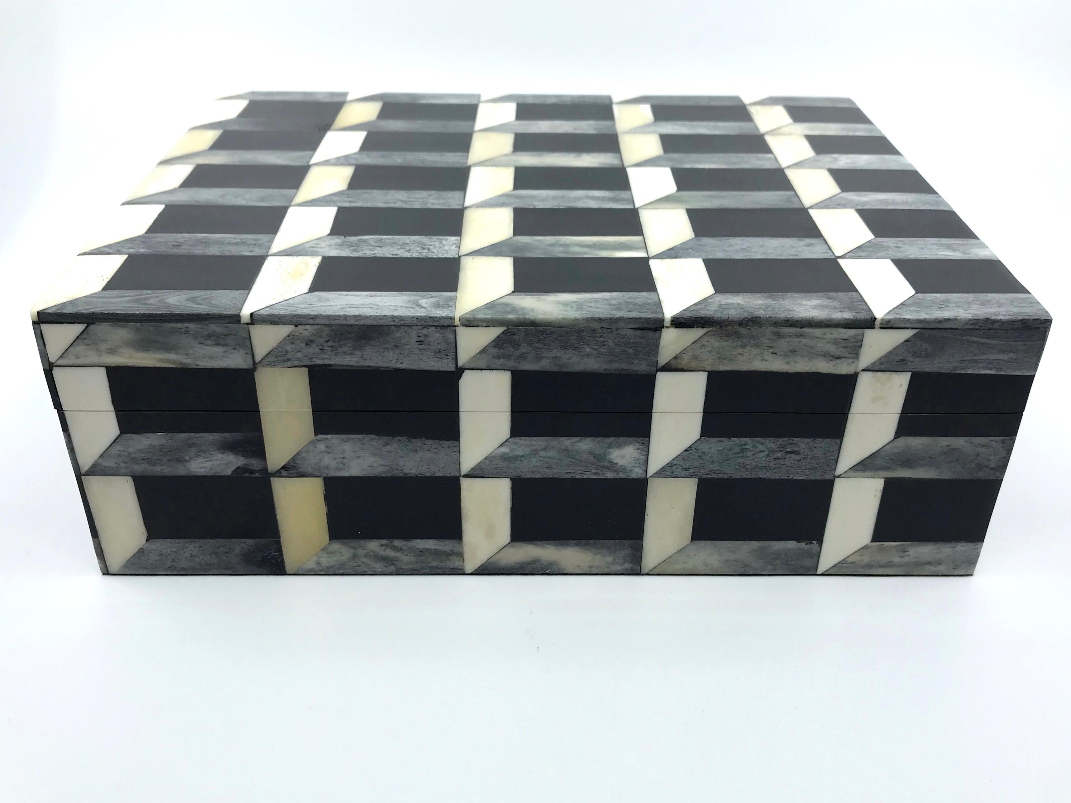 Black, grey and cream horn and bone geometric inlay box. Handsome hand-crafted geometric inlay box great reminiscent of Roman marble work; perfect for storing remotes. Asia, 20th Century
Dimensions: 9.25
