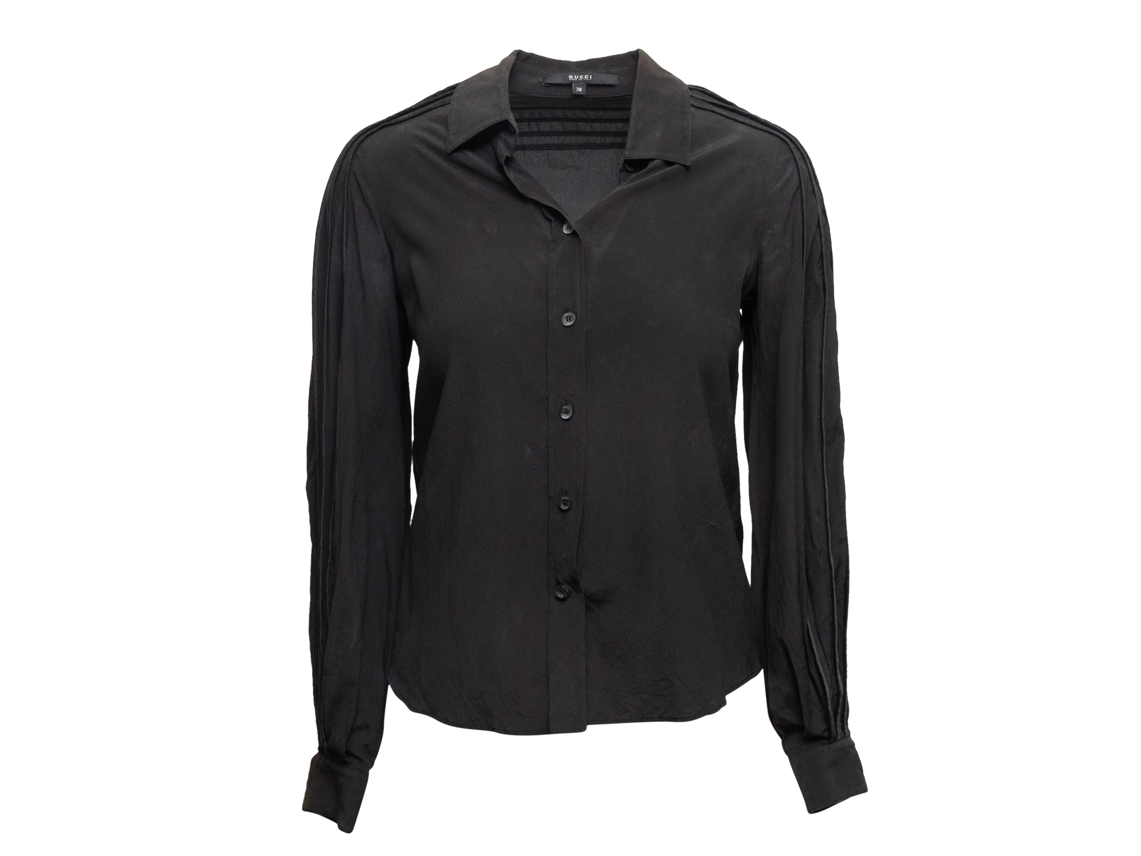 Top boutonné à manches longues en soie noire, signé Gucci. Col pointu. Plis aux manches. Fermeture par boutons au centre du devant. Poitrine de 33 pouces, largeur d'épaule de 16 pouces, longueur de 23,5 pouces. 