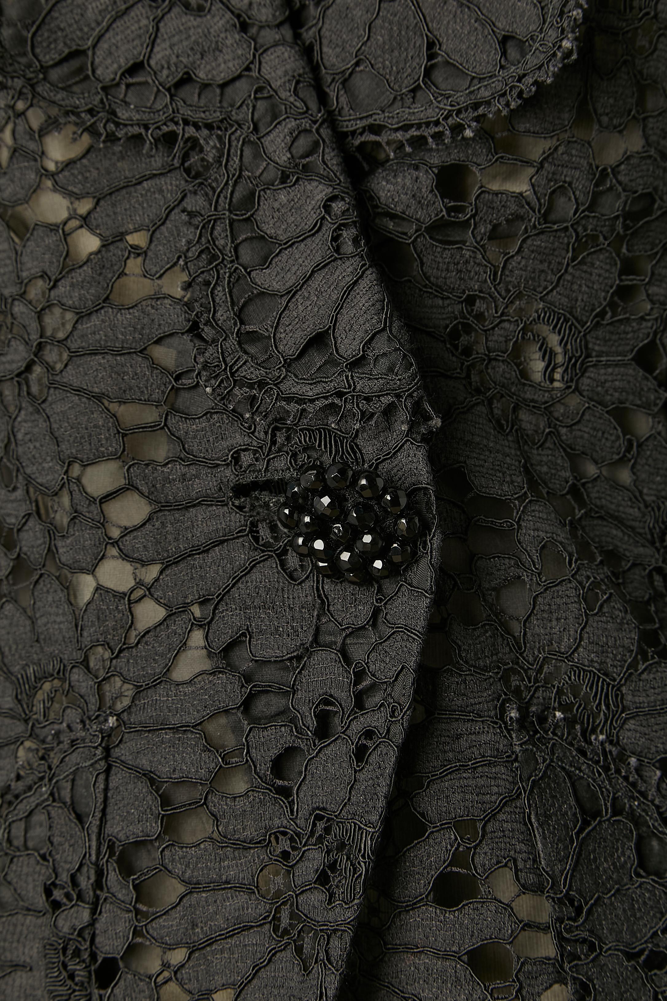 Schwarze Abendjacke aus Guipure mit schwarzen Perlenknöpfen. Schwarzes Organzafutter. Perlenbesetzte Knöpfe auch an den Manschetten. Schulterpads. Ein Druckknopf und ein Haken&Öse in der vorderen Mitte. 
GRÖSSE S / 36 (Fr) 