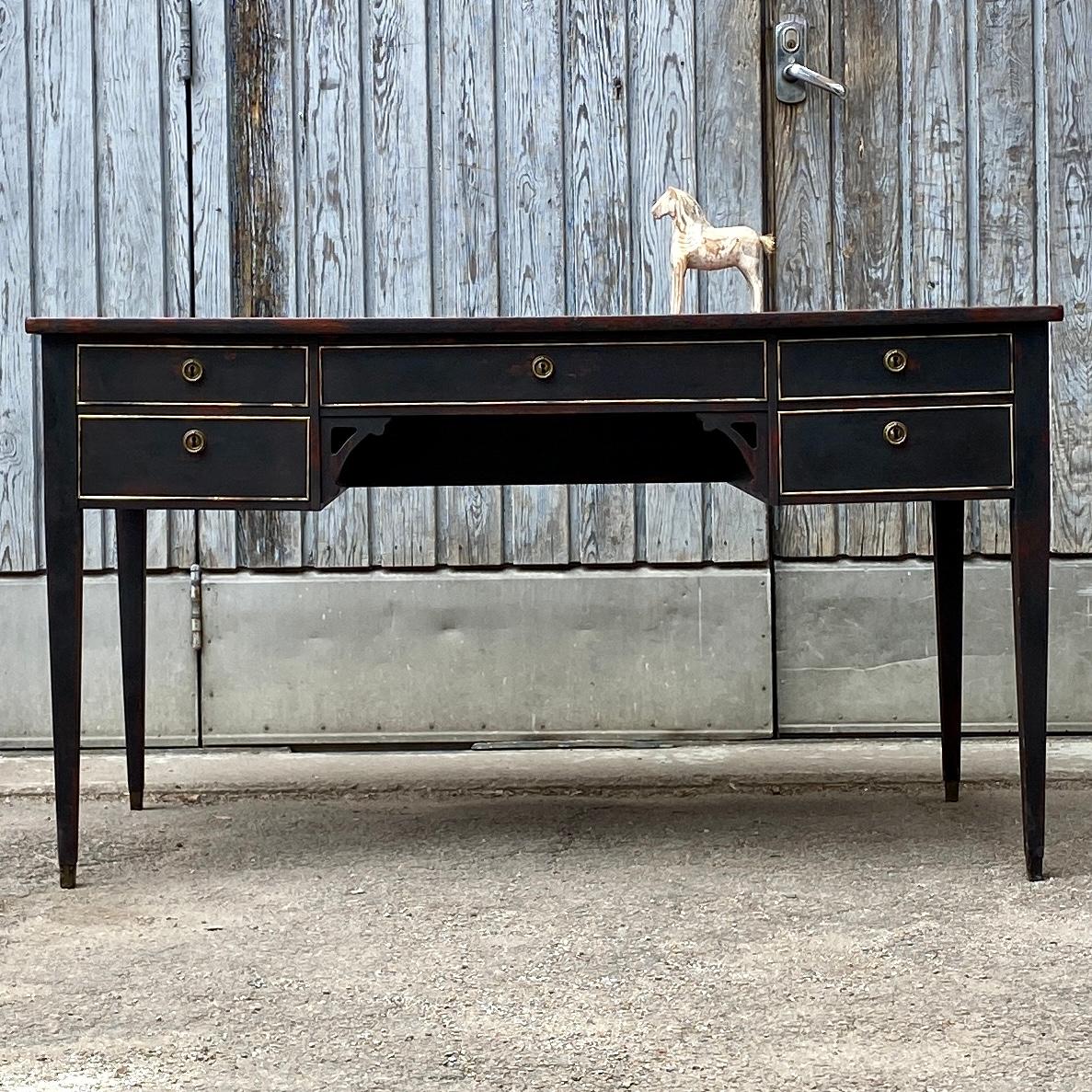 Swedish office writing desk in Gustavian black paint with five drawers, red leather embossed top and the original brass hardware.
