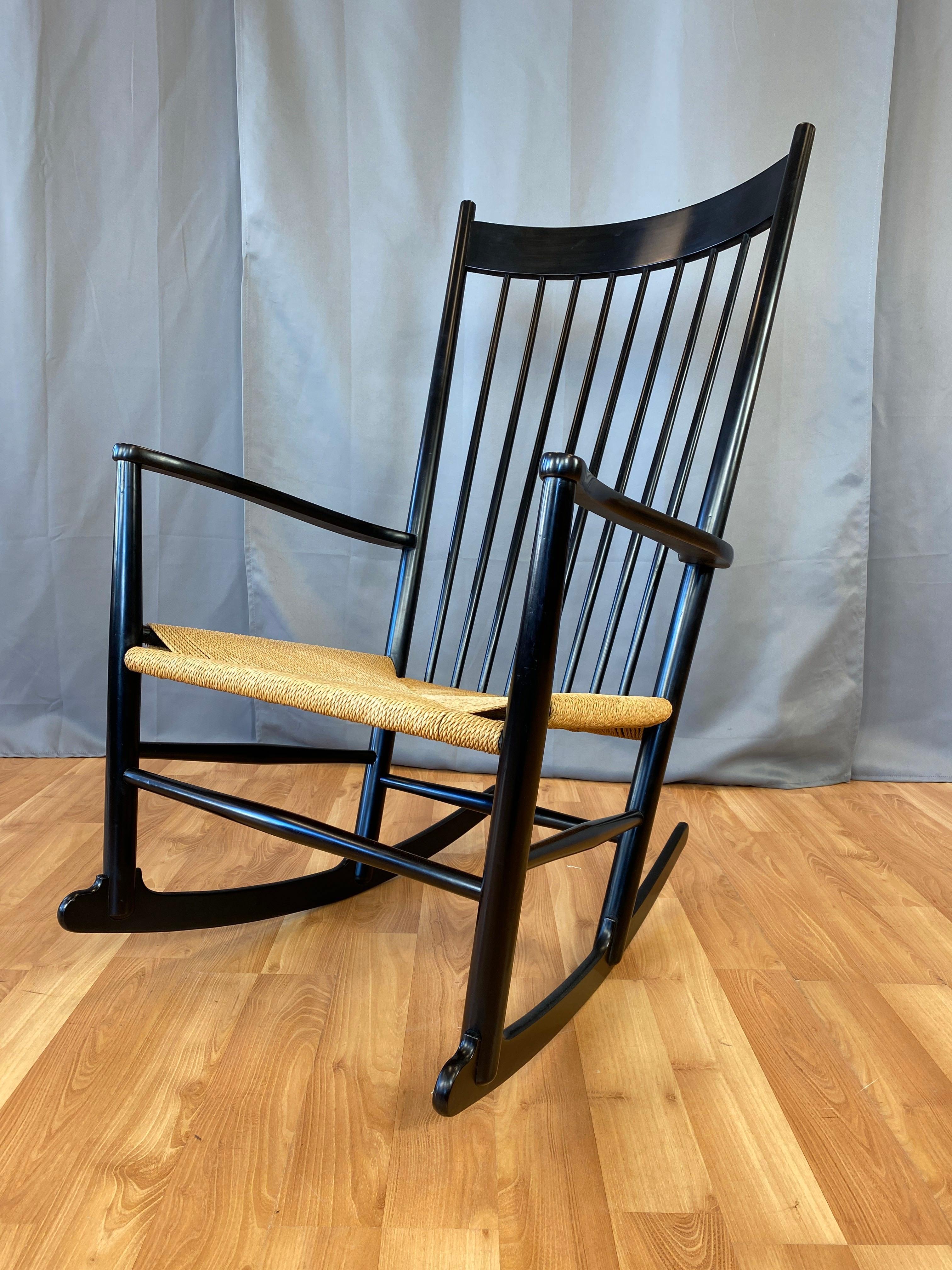 A generously proportioned model J-16 rocking chair, looks to be recently painted black, with woven paper cord seats. 

A Classic and comfortable design first introduced in 1944, these high-backed ergonomic rockers feature tapering spindles,