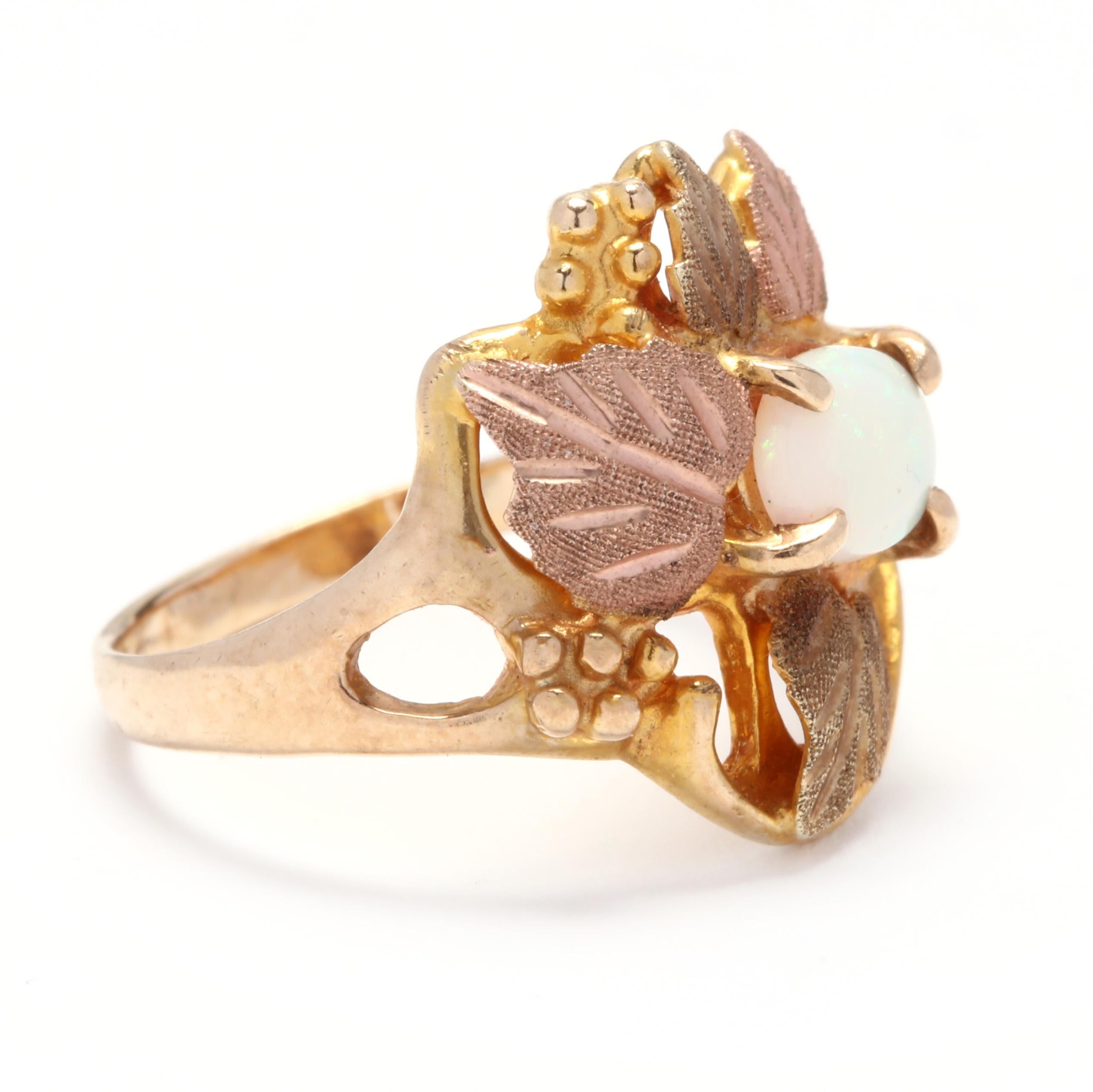A vintage Black Hills 10 karat tricolor gold and opal leaf ring. A yellow gold ring with a cluster green and rose gold leaf motifs and a prong set, oval cabochon opal. 

Stones:
- opal, 1 stone
- oval cabochon
- 7.15 x 5.15 mm
- approximately .50