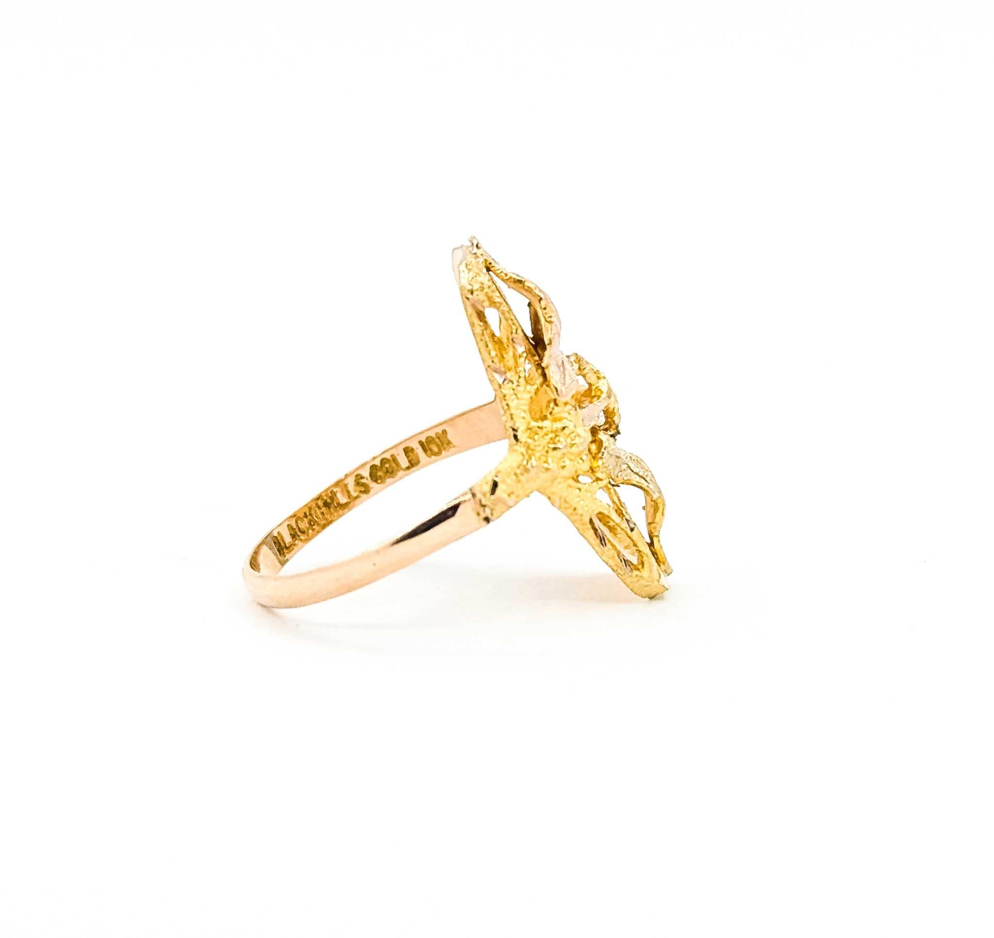 This charming ring is crafted in 10k tri-color gold and features the signature Black Hills Gold design. The piece showcases beautifully detailed rose, green, and yellow gold leaves arranged in an elegant vertical motif. The textured and polished