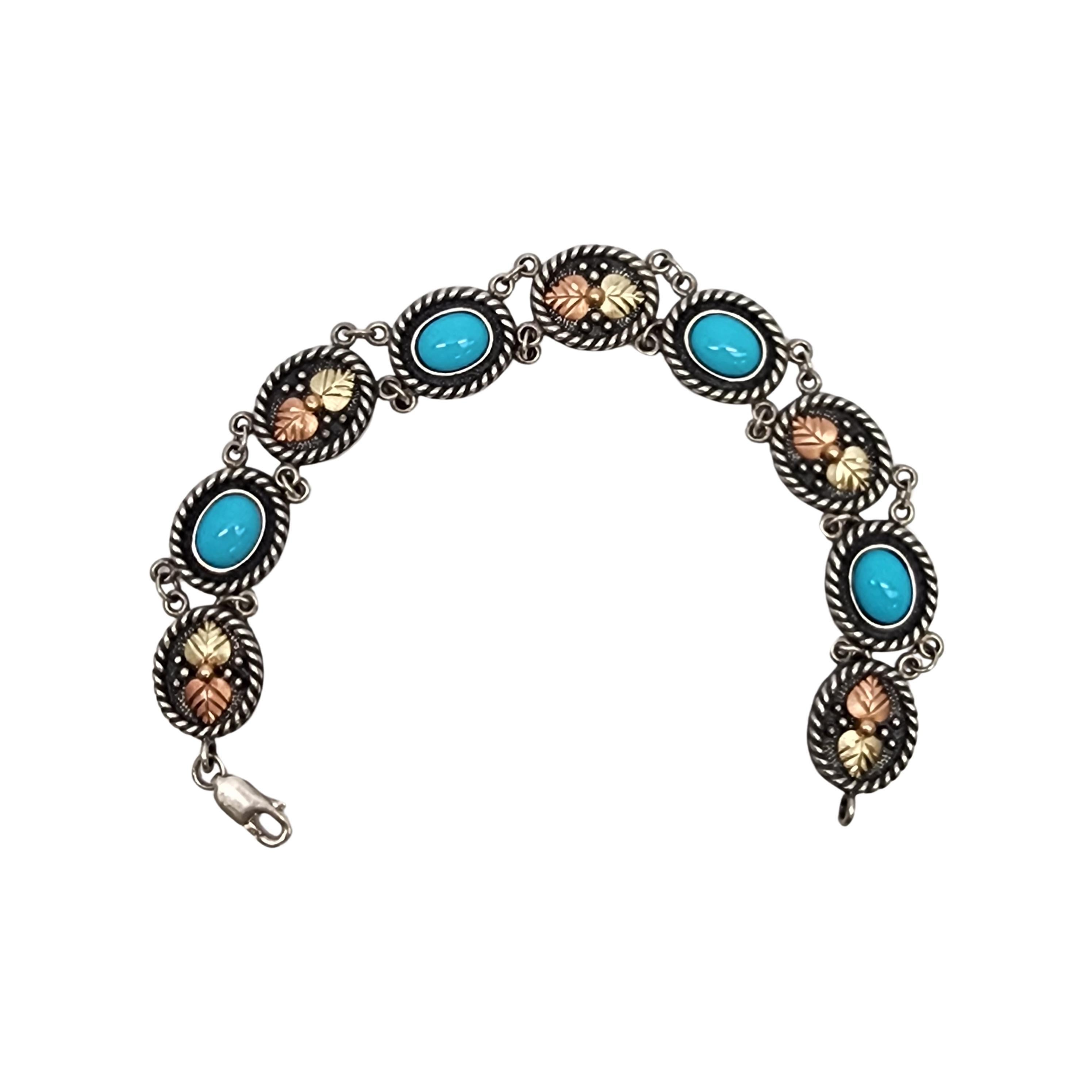 Sterling silver 10K leaf and turquoise link bracelet by Black Hills Gold.

Oval links feature a bezel shaped turquoise stone alternating with links featuring 10K yellow and rose gold leaves, all links are framed in a rope design. Lobster claw