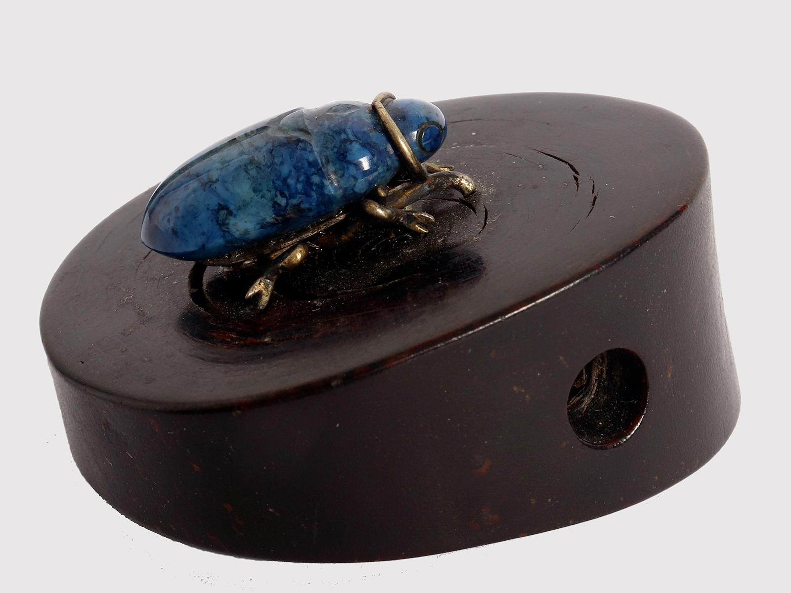 Black monochrome horn netsuke emulating an asymmetrically sectioned tree trunk. Along the top climbs an insect carved in lapis lazuli and finished with gold details. Japan, Meiji period (1867-1912), around 1870.